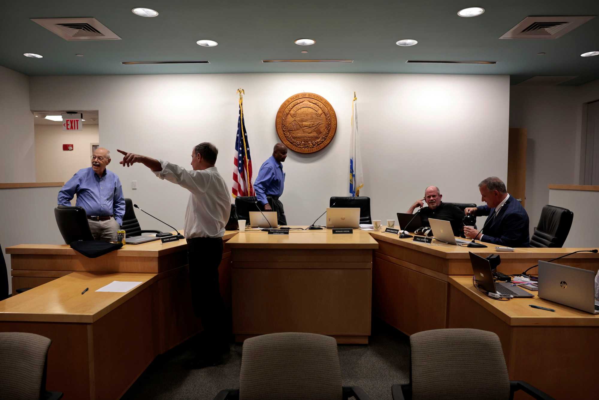 Select Board member Michael Sandman (left) talked with David Pollak, a member of a committee studying Brookline's rezoning efforts, as Select Board Chair Bernard Greene and members John VanScoyoc and Paul Warren prepared for the start of a September hearing. (photos by Craig F. Walker/Globe Staff) 
