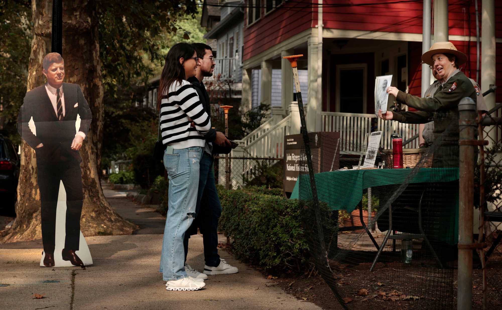 A cut-out of President Kennedy was placed outside his birthplace in Brookline. Visitors Angelica Rodriguez and George Reid talked with ranger Eleanor Katari outside the national historic site on Beals Street near Coolidge Corner. 

 