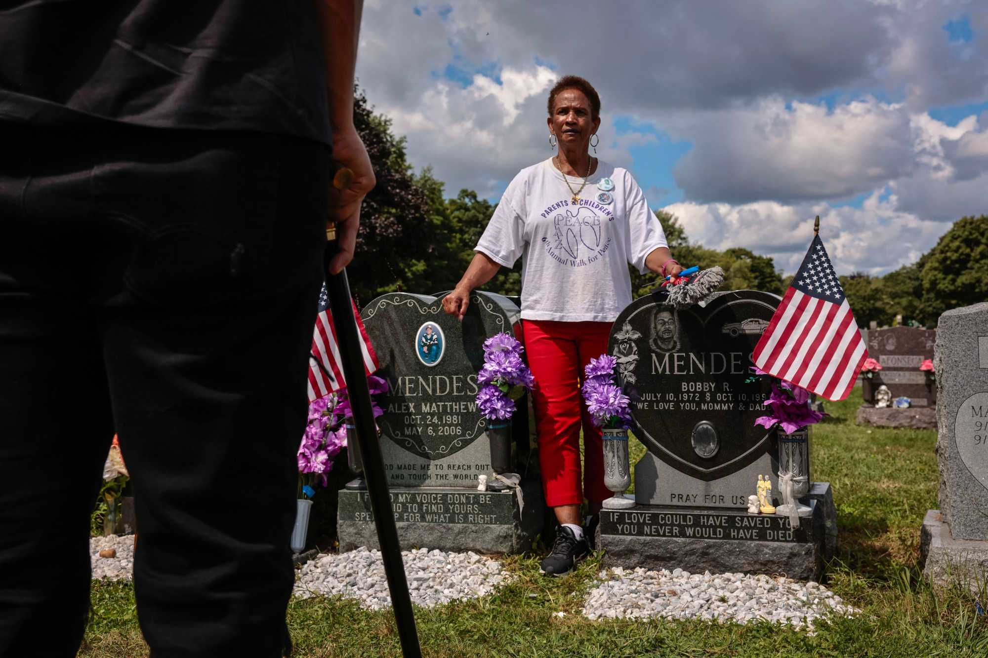 Isaura Mendes spoke with Milton DoSouto at the graves of her slain sons, Matthew and Bobby, at New Calvary Cemetery in Mattapan. DoSouto's brothers, Luis and Alex, both also victims of deadly street violence, are buried just steps away. 
