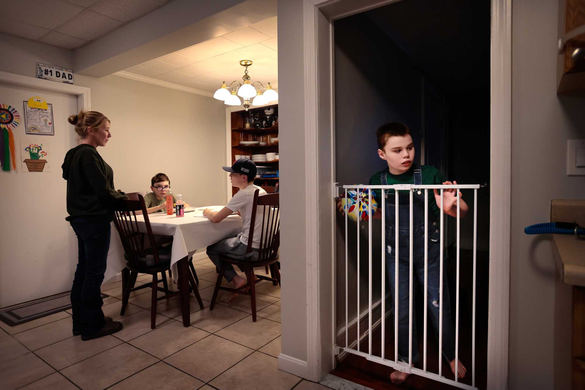 Dante Fowler, 12, peered over the gate while his mother, Jen, served dinner to his brothers, at their home in Wakefield in February. To ensure his safety, Dante is confined to the living room and the bedroom he shares with his twin brother, Nino. Jen said feels guilty she never gets to sit and eat dinner with her other children.