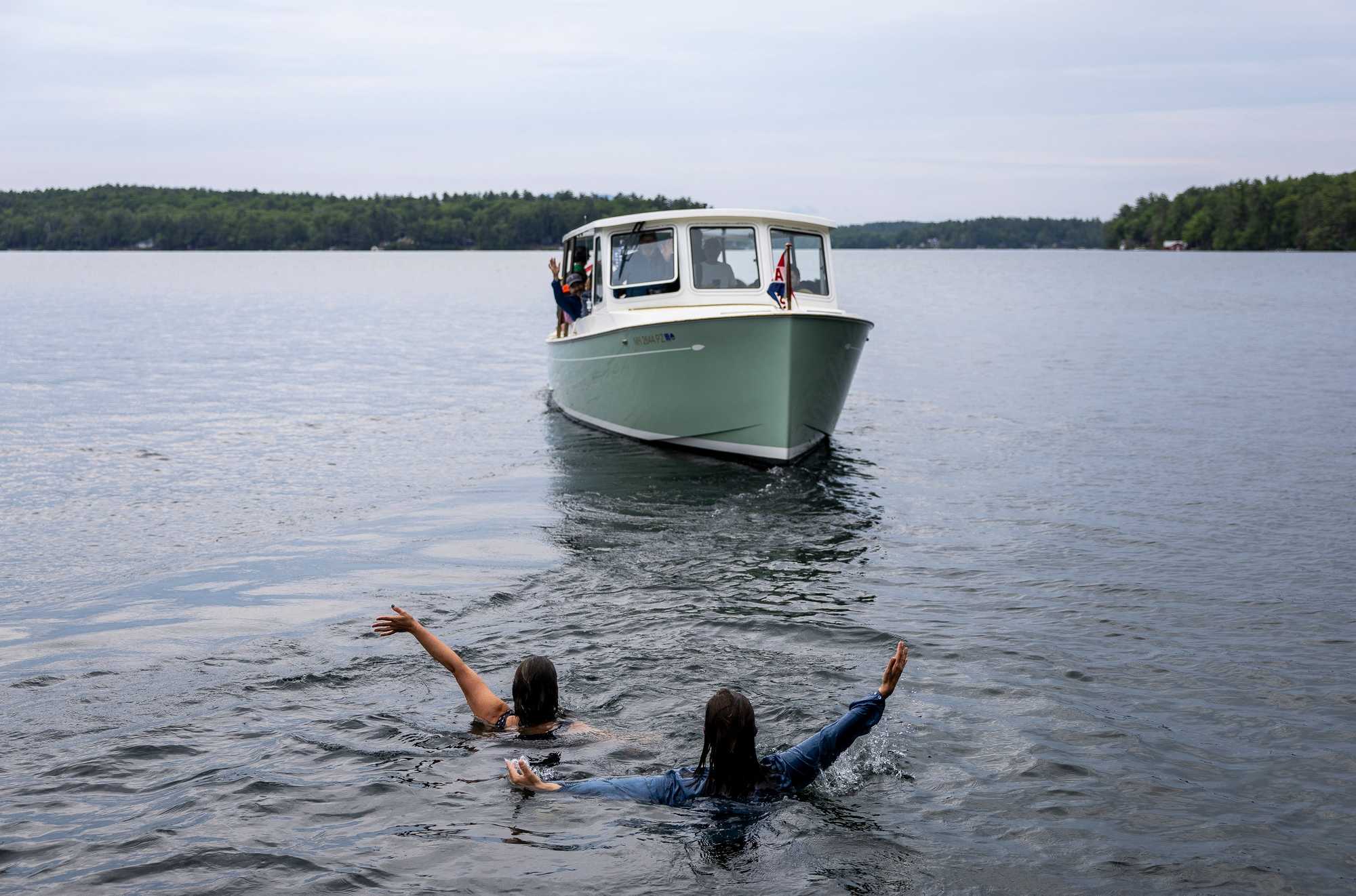Camp directors Kristin Andreassen and Lauren Balthrop wave to departing campers from Lake Winnipesaukee.