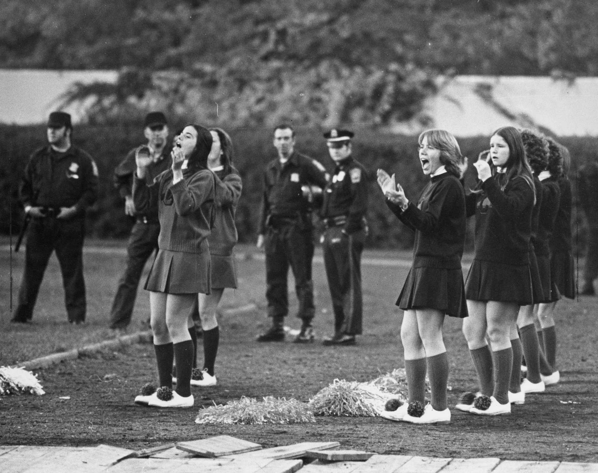 Cheerleaders take the field alongside a line of Tactical Patrol Force officers during a South Boston-Dorchester game on Oct. 23, 1975.