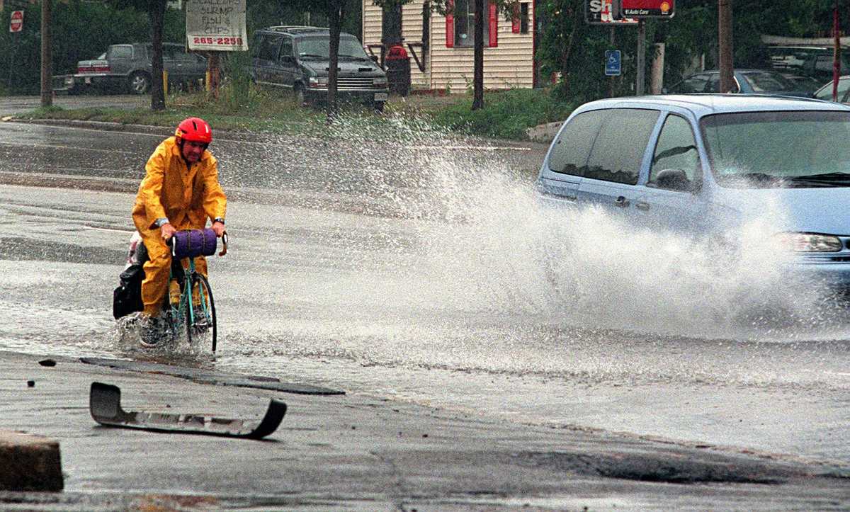 An intrepid cyclist skimmed the edge of large puddle during heavy rains on Morrissey Boulevard in 2000. (George Rizer/Globe Staff)
