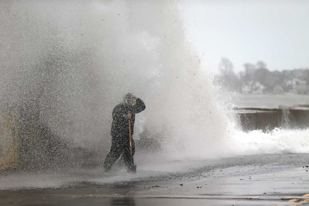 Crews clearing catch basins on Winthrop Parkway in Revere were hit by a wave coming over the sea wall during high tide in December 2022. (Jonathan Wiggs/Globe Staff)