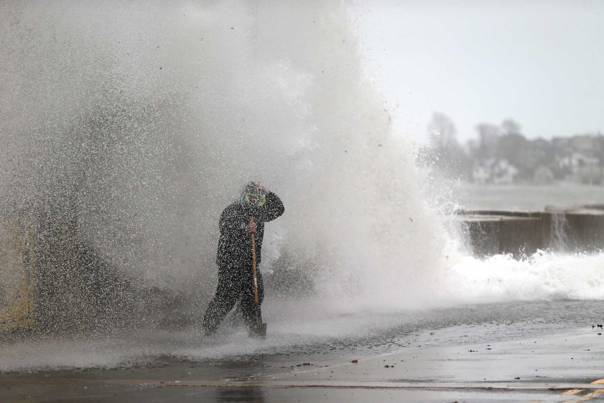 Crews clearing catch basins on Winthrop Parkway in Revere were hit by a wave coming over the sea wall during high tide in December 2022. (Jonathan Wiggs/Globe Staff)