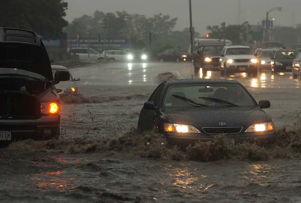 A driver braved knee-deep water on Morrissey Boulevard, passing another vehicle that had gotten stuck in the water in June 2006. (Essdras M. Suarez/Globe staff)
