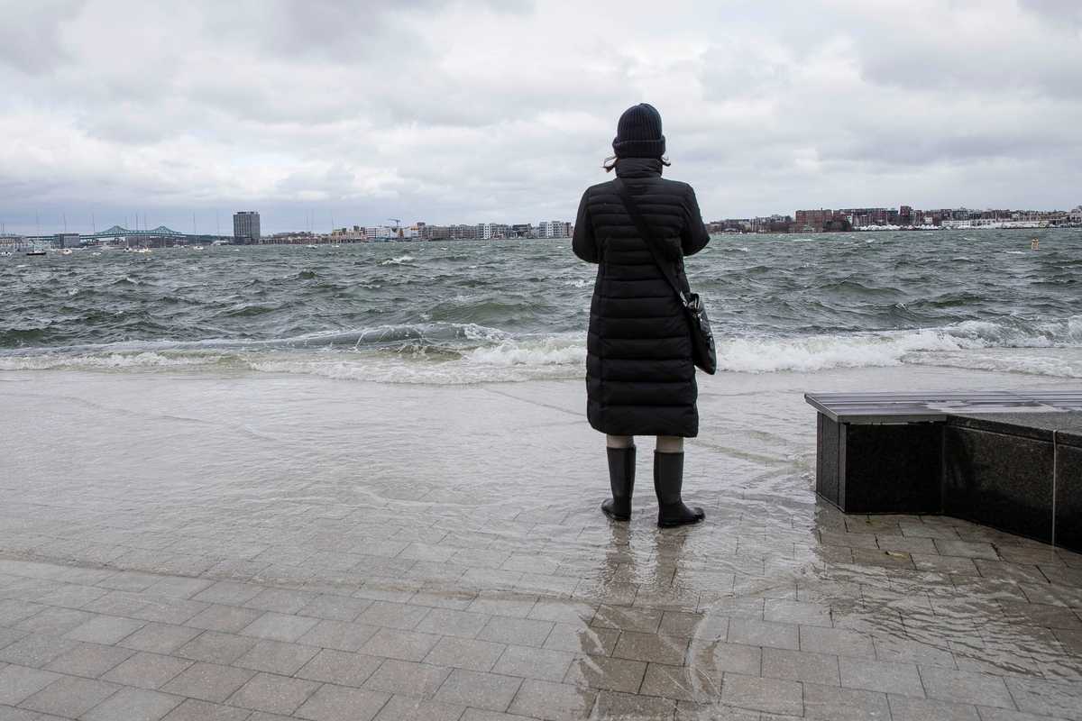 A woman watched as waves crashed into Fan Pier in the Seaport District during a nor'easter on March 3, 2018.  
(Keith Bedford/Globe Staff)