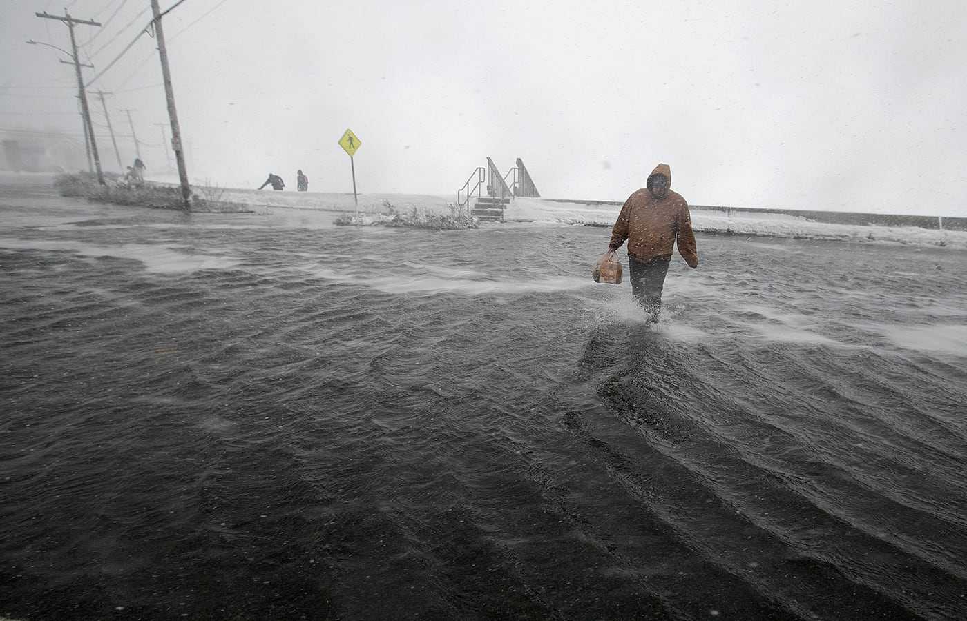 A man walked across flooded East Squantum Street in the Squantum section of Quincy, during a storm that cut off the peninsula in 2018.