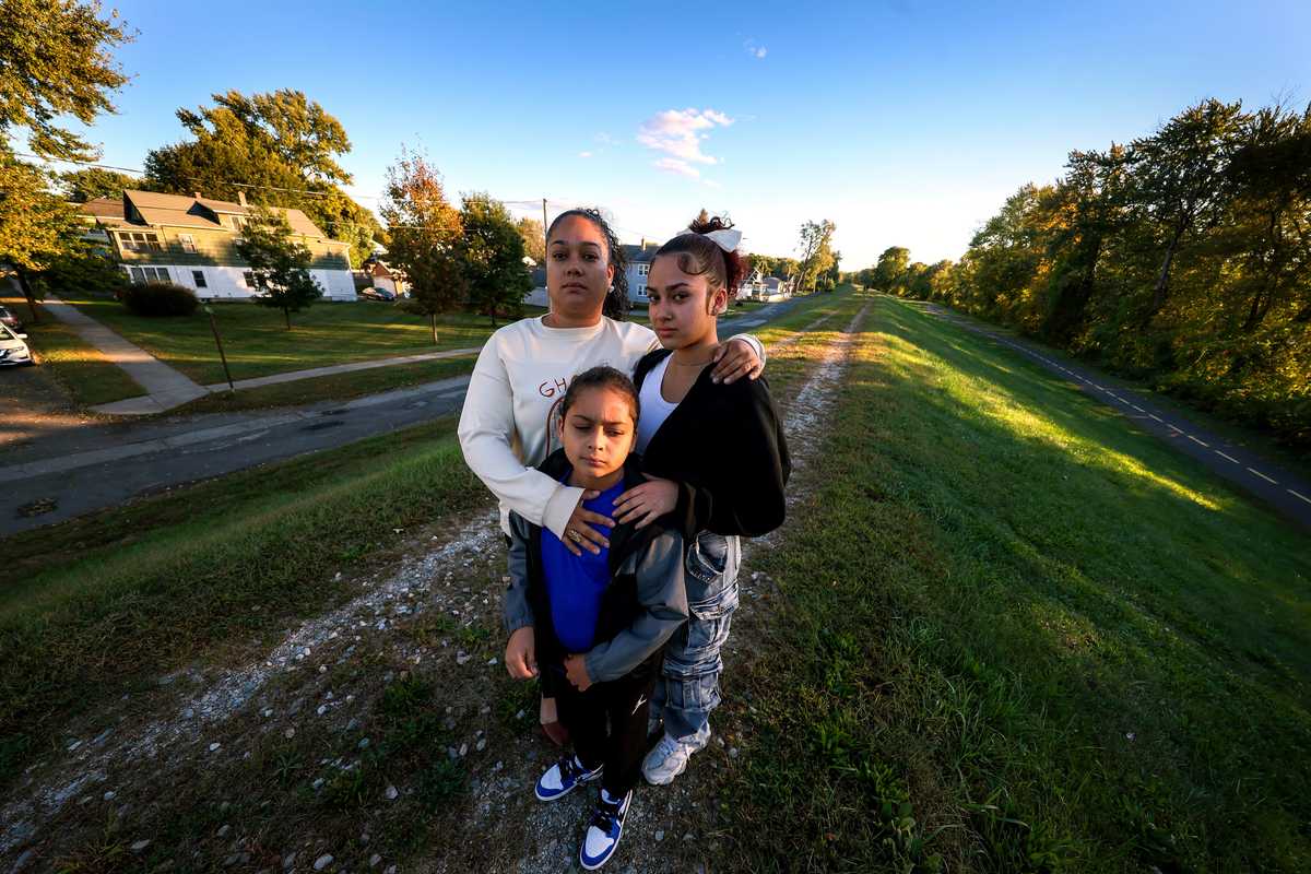 Catherine Gonzalez with her son, Kyrie Cortez, 8, and daughter, Paula Cortez,16, stood atop the levee that is a few houses away from her home in the Willimansett neighborhood of Chicopee. (Barry Chin/Globe Staff)