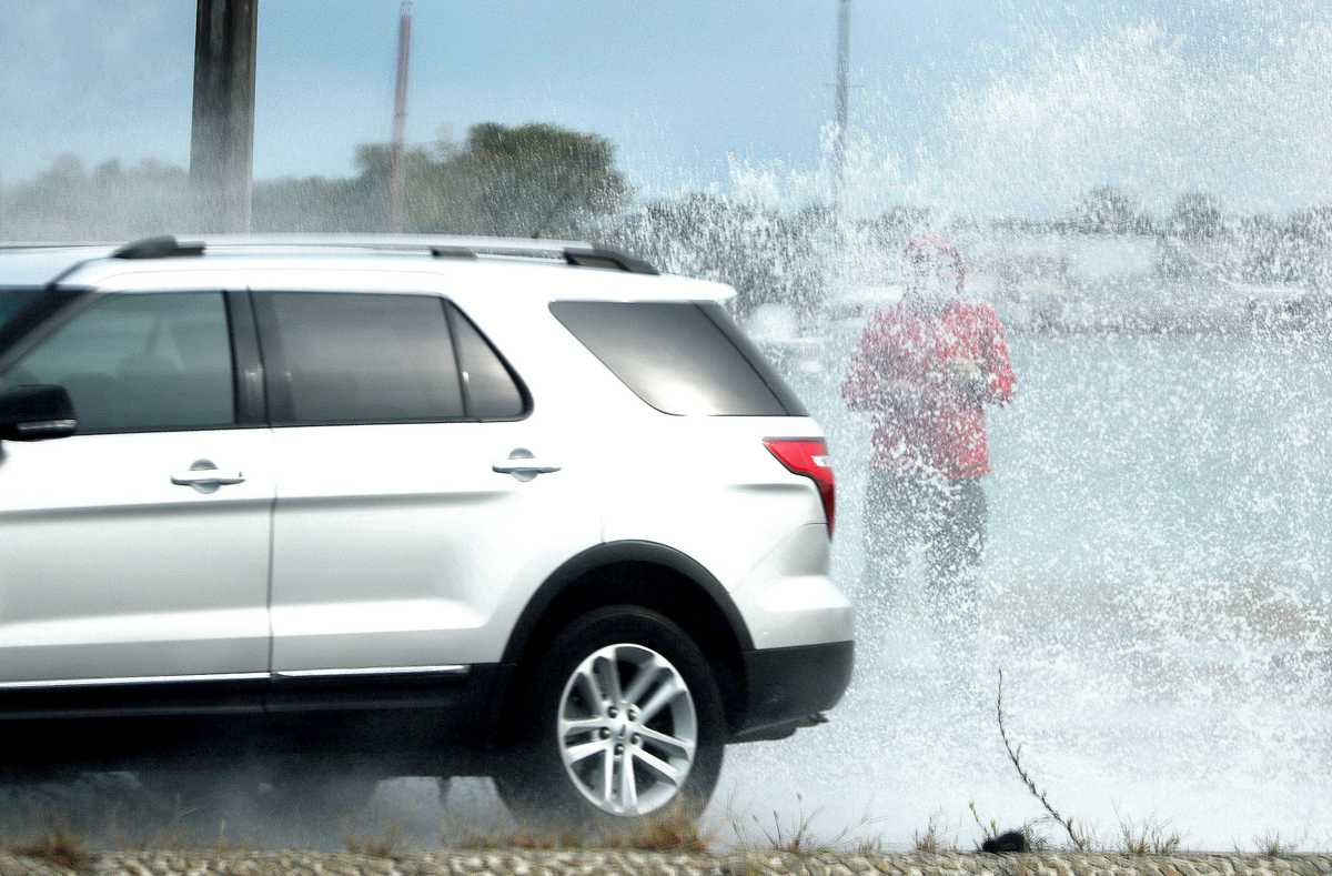 A passerby was hit by spray from vehicles during high tide flooding along Morrissey Boulevard in 2020. (Barry Chin/Globe Staff)