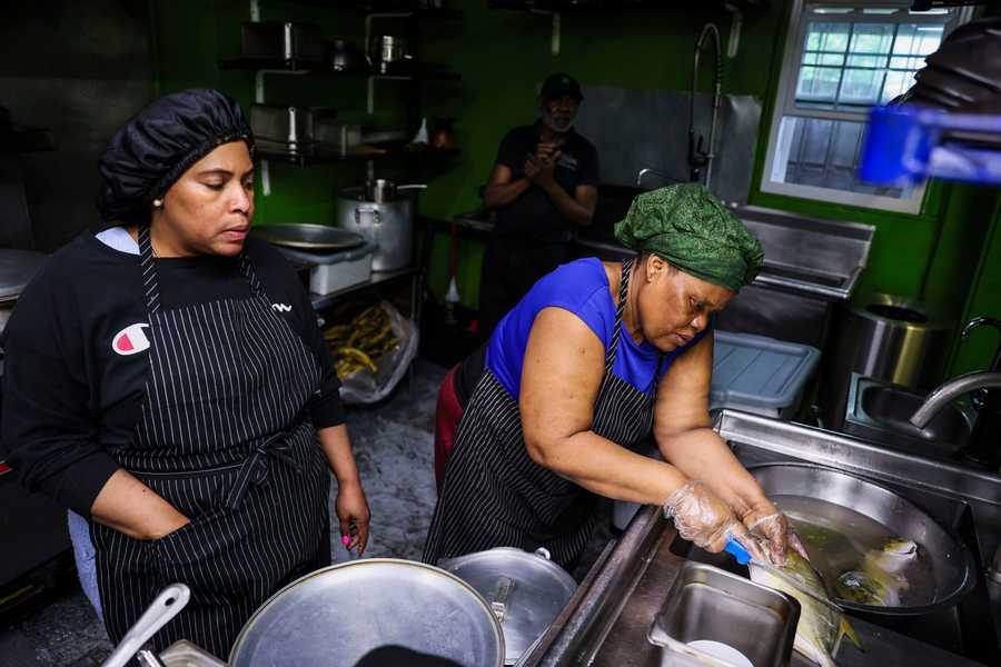 BOSTON, MA - 4/20/2024 Marie Dessain, left, watches as Rosenie Cange prepares fish in lime juice and water while working at Divine Merci, a Haitian restaurant in Mattapan owned by Marie Dessain and her husband, Jean Nelson. The restaurant used to be busy before the pandemic, said Nelson. But now, business is slow and most customers choose to take their food to-go rather than eat in the restaurant. To increase business, the couple has decided to apply for a liquor license. Erin Clark/Globe Staff, xxlicenses1
xxlicenses1 