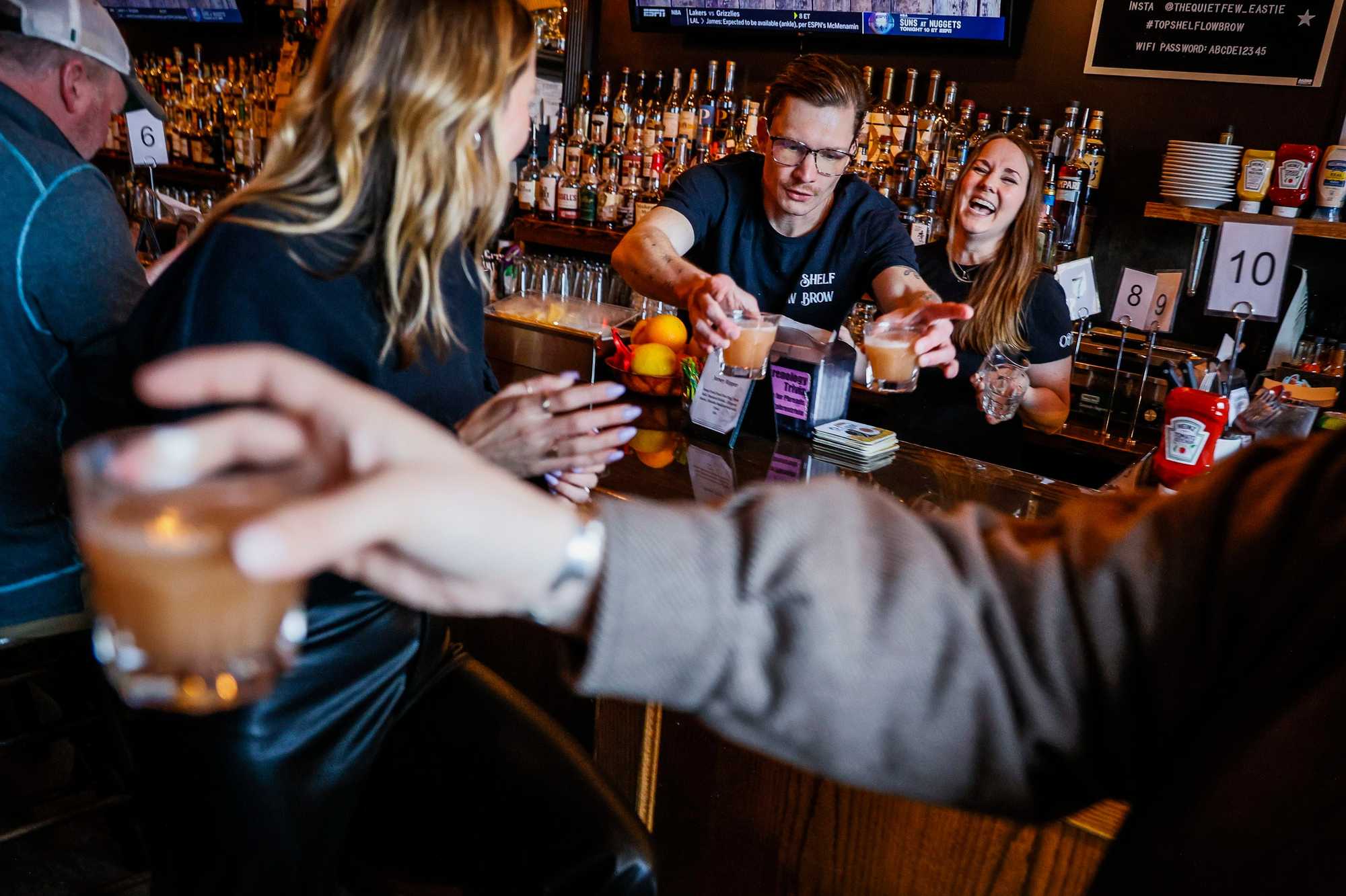 Peter Lesser and Gwen Hagerty, bartenders at The Quiet Few, serve whiskey drinks while working behind the bar on a Wednesday night. 