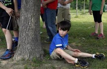 During recess at his elementary school, Strider sat at the base of a tree as other children played nearby.