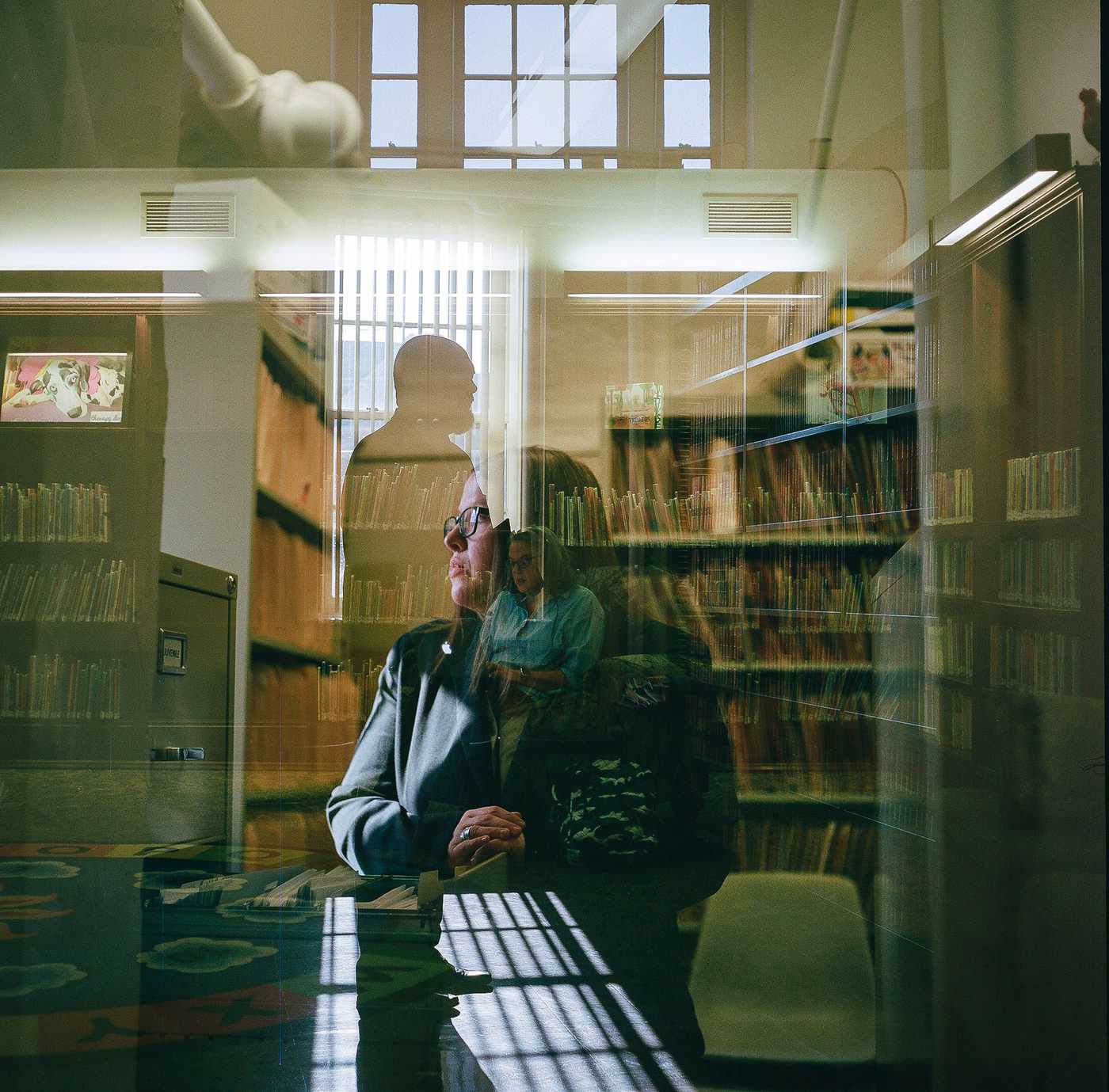 A triple-exposure of Kate in the library she visited as a child, overlaid with a portrait of Daniel Lynn, a Columbia County assistant district attorney, and Janelle Neidig, a victim/witness coordinator.

