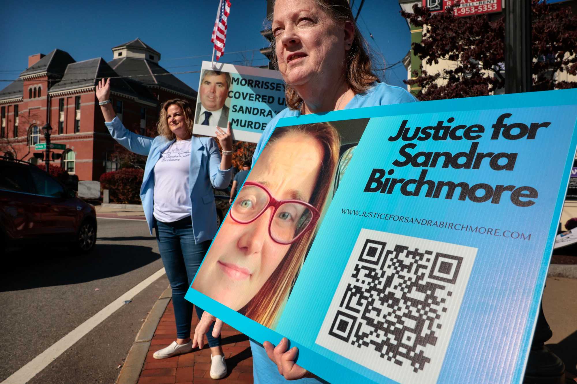 Barbara Wright (at right), one of Birchmore's cousins, holds a sign near Stoughton Town Hall in October. 