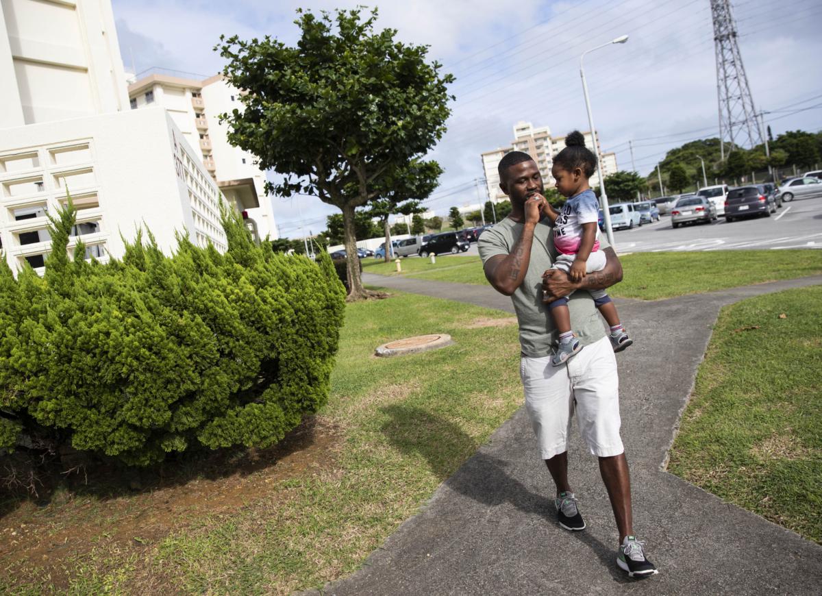 Blackwood, seen here carrying his son Micah near his apartment complex in Okinawa, Japan, is a world away from the future he’d once imagined for himself.