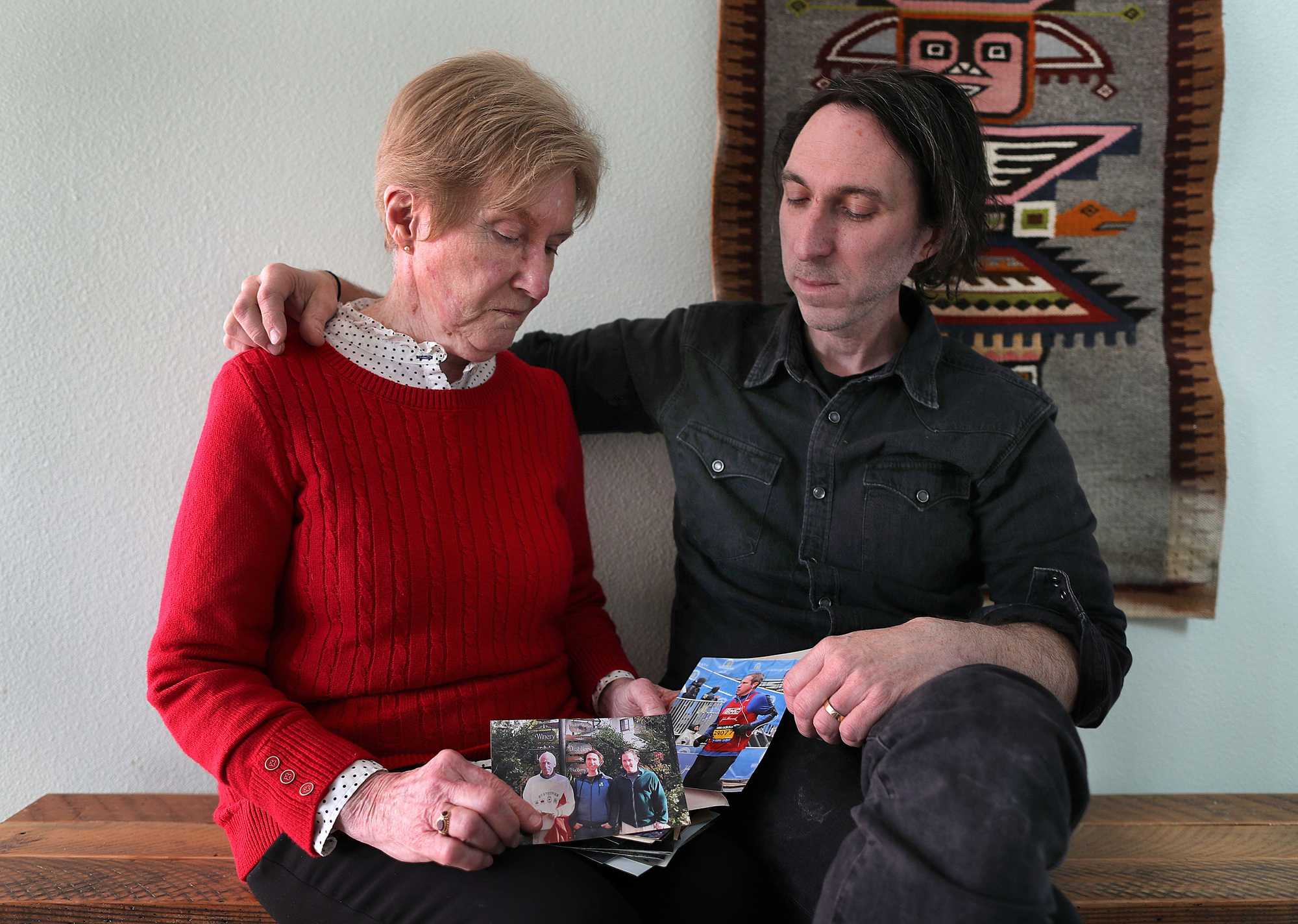 Mary Jo White sat on a bench with her son, Andrew White, at his home and looked at photos of her husband, Bill, (left photo) and son Kevin. Mary Jo and Bill were injured when the first bomb went off at the Boston Marathon in 2013. Bill lost his leg and Mary Jo suffered from shrapnel wounds to her legs and body. Kevin was also injured that day as spectator. Kevin died in 2015, and Bill died in December in 2022 in Oregon. 