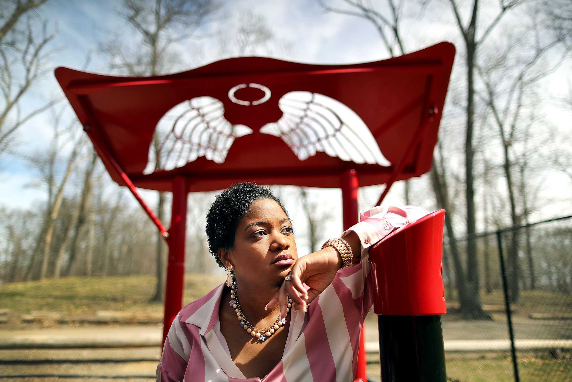 Nicole Simmonds-Jordan stood near an angel wings carving at a playground in Belcher Park in Randolph that was built in tribute to her late brother, Boston Police Officer Dennis "DJ" Simmonds. 