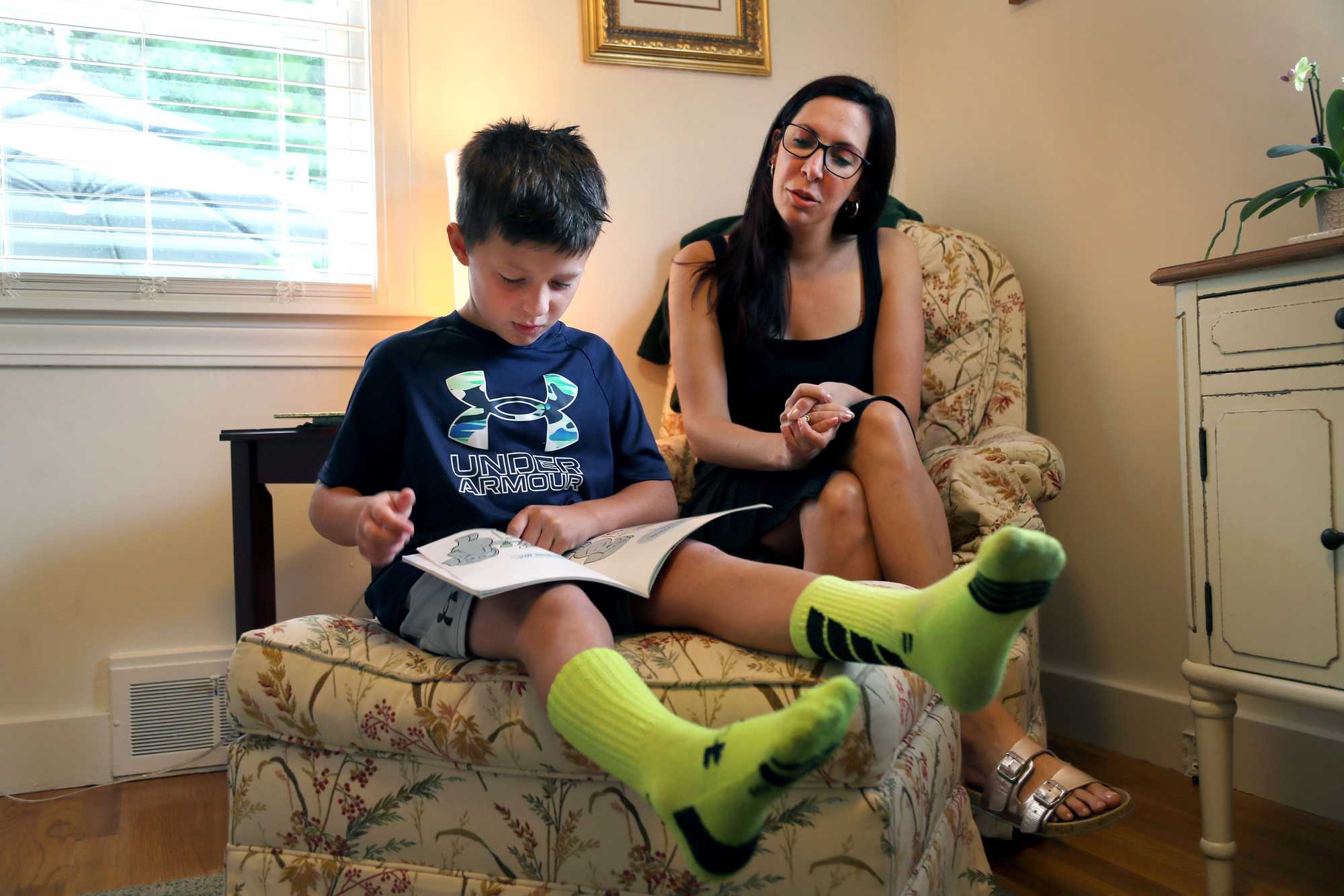 Carmine Coy, 7, read a book at home in Reading as his mother, Lauren Andreottola, listened.