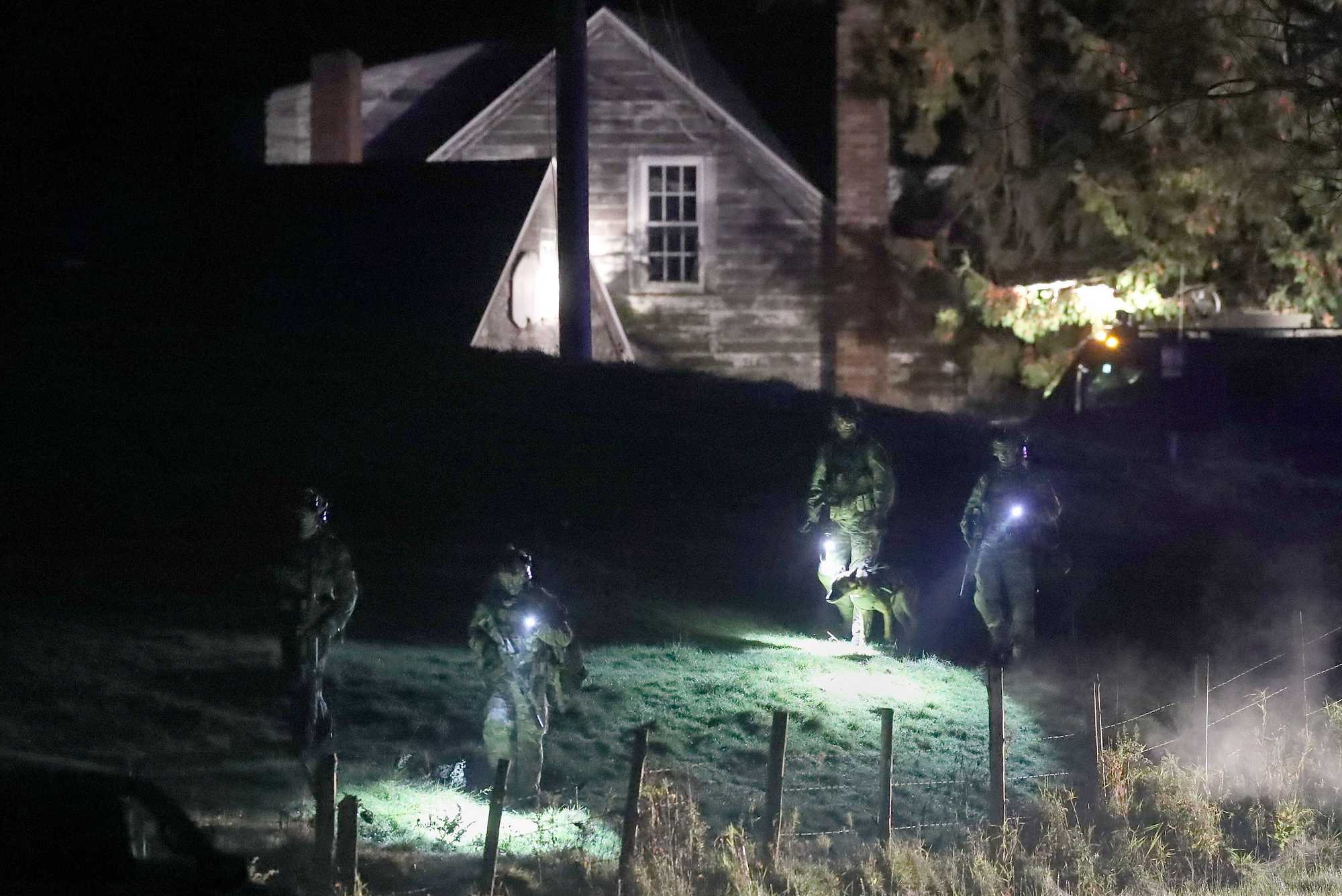 With the aid of a canine unit, police on Oct. 26 searched a rural property belonging to the father of gunman Robert Card on Meadow Road in Bowdoin, Maine. The gunman was still at large a day after the mass shootings, which forced a lockdown of multiple Maine communities.