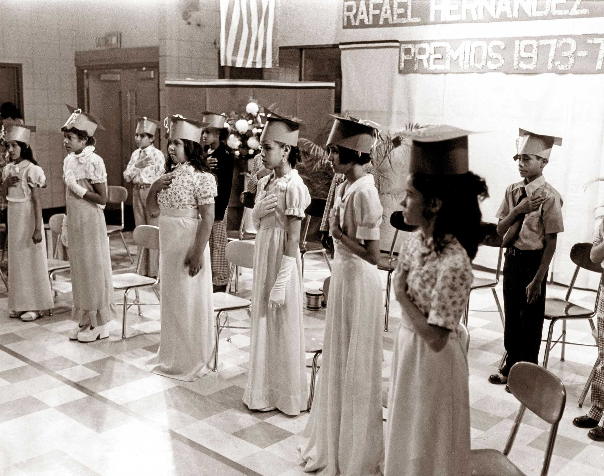 The 1973-74 graduating class of the Rafael Hernández Dual Language School stood for the playing of the Puerto Rican National Anthem. (Jack O'Connell/Globe Staff)