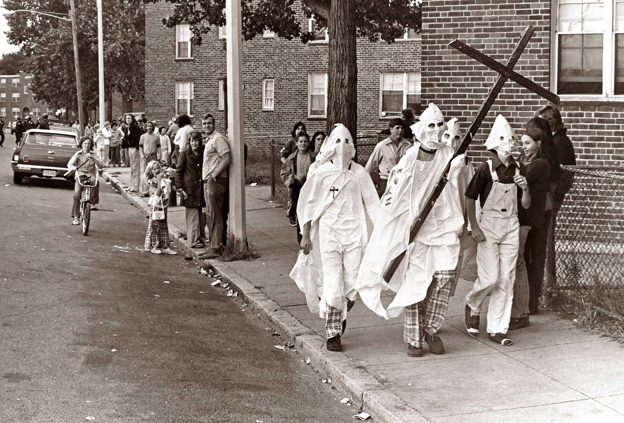 A group of Ku Klux Klan impersonators carried a large cross as they walked past the Old Colony housing project on Columbia Road in Boston on Sept. 18, 1974.