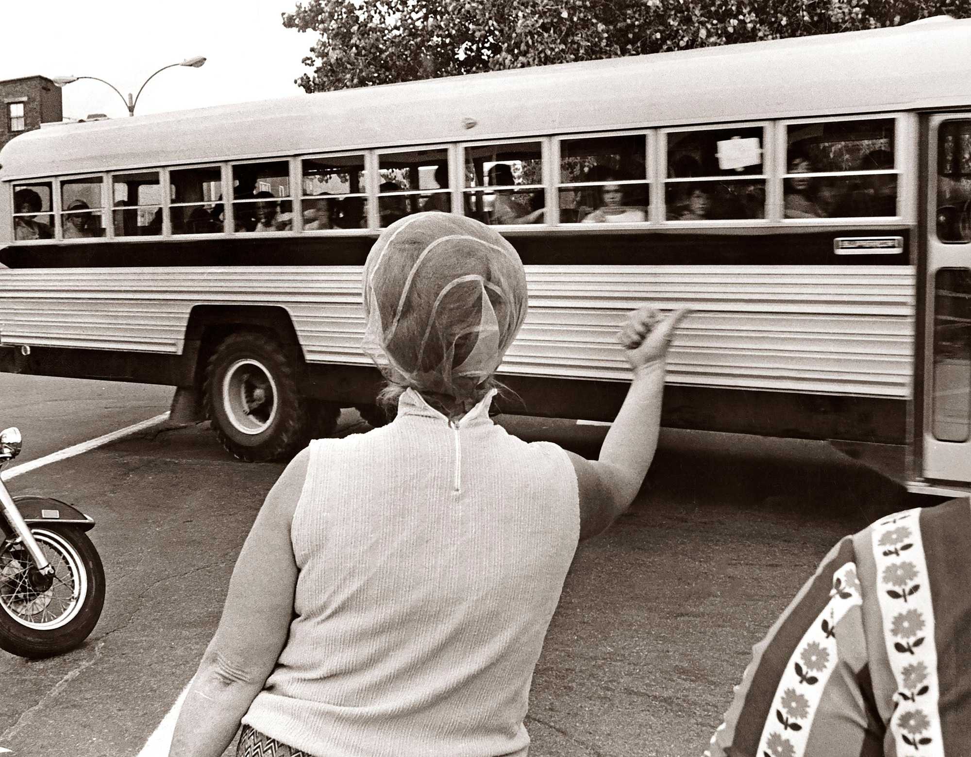 A woman gestured for students being bused home to Roxbury to "Go home and stay home," as a school bus left Patrick F. Gavin Middle School in South Boston on Sept,17, 1974, during the first full week of school under the new busing system put in place to desegregate Boston Public Schools