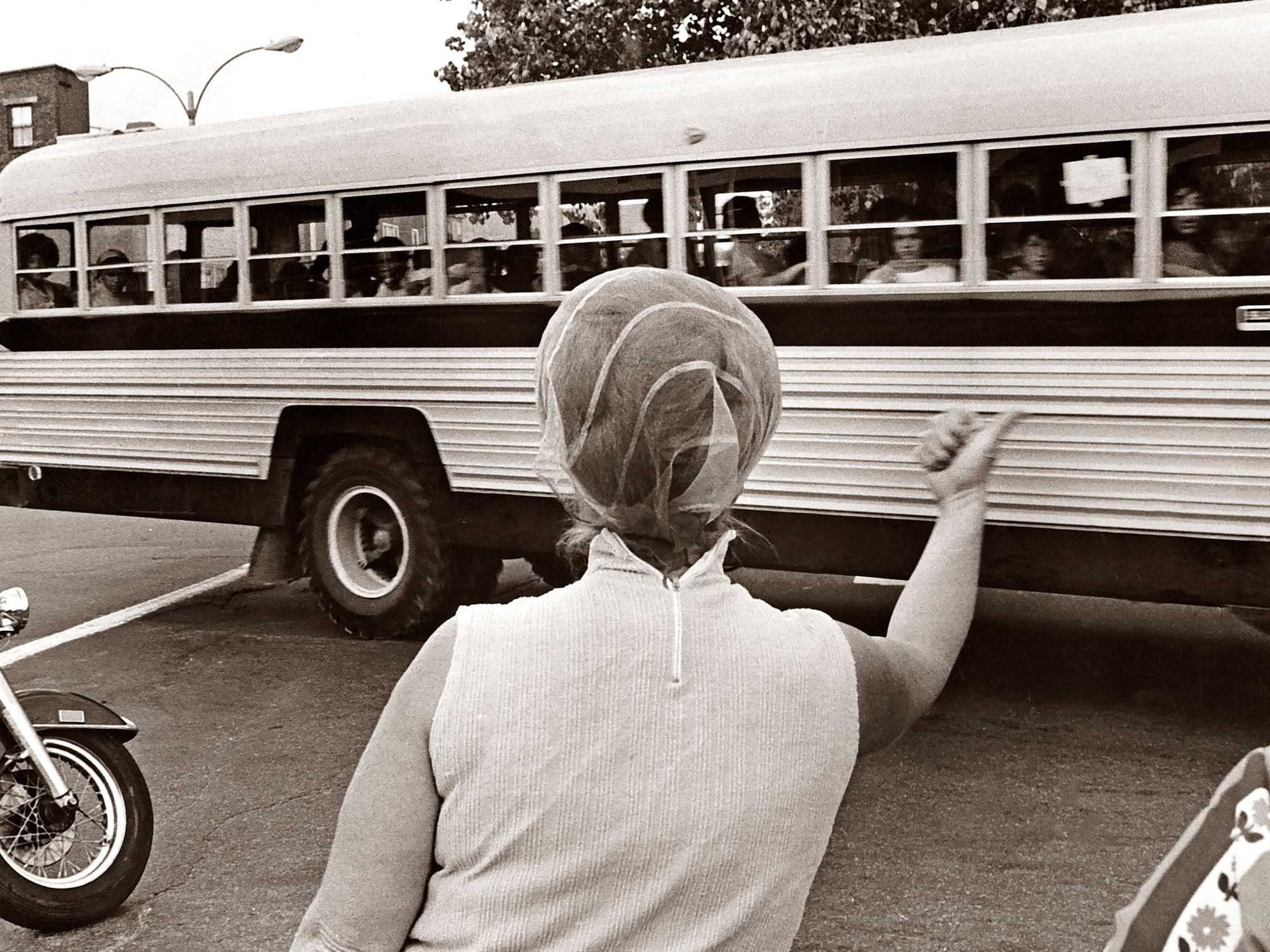 A woman gestured for students being bused home to Roxbury to, "Go home and stay home," as a school bus leaves Patrick F. Gavin Middle School in South Boston on Sept. 17, 1974. It was the first full week of school under the new busing system put in place to desegregate Boston Public Schools. (Charles Dixon/Globe Staff)