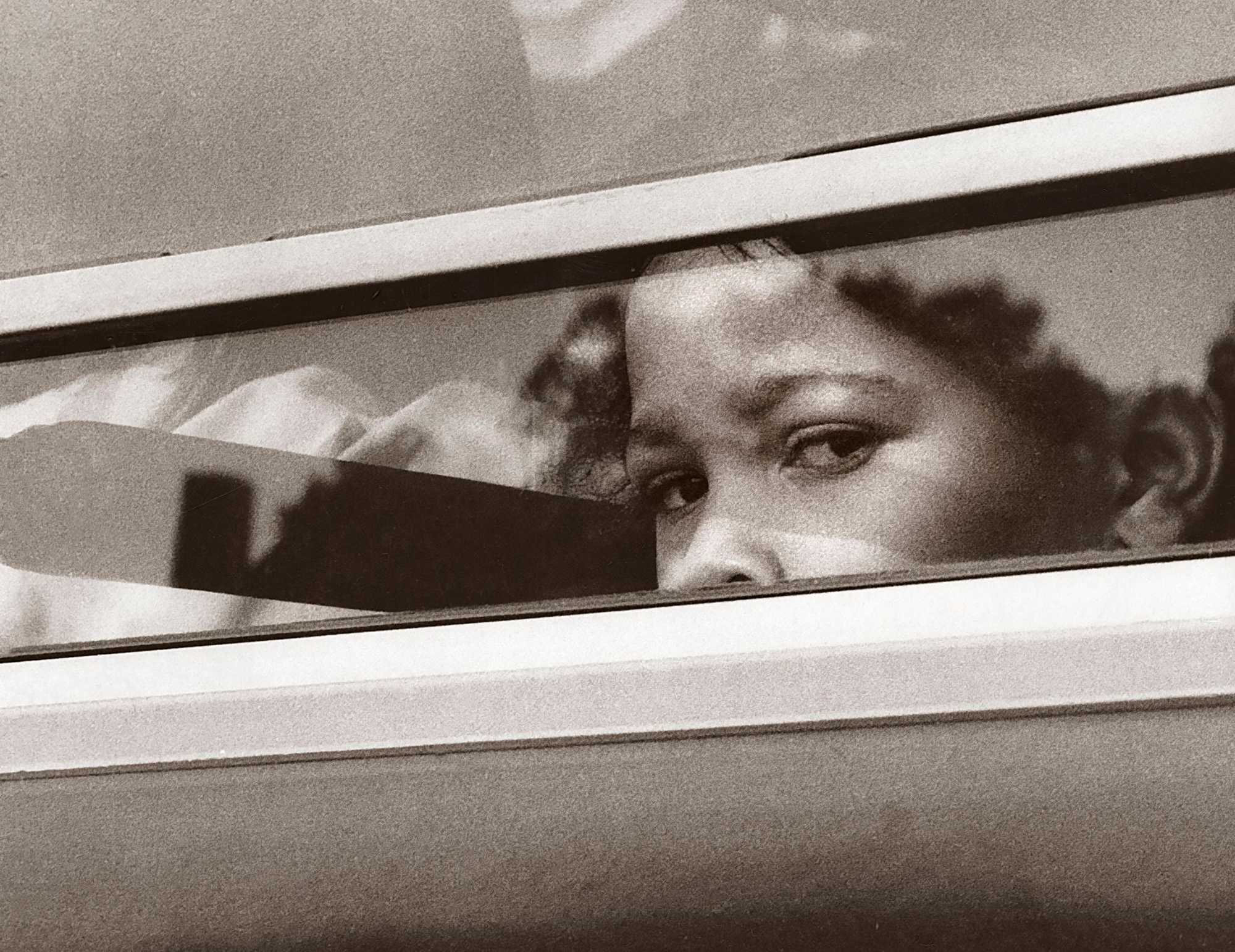 A young girl looked out of a bus window on her way to a new school in Boston on Sept. 12, 1974, the first day of school under the new busing system put in place to desegregate Boston Public Schools.  (Bob Dean/Globe Staff)