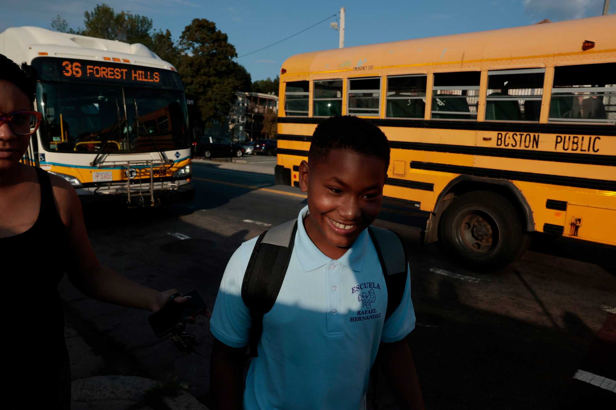 José María, estudiante de quinto grado, sonríe frente a su autobús escolar en la intersección de las calles Washington y Archdale mientras camina hacia la escuela Rafael Hernández el 7 de septiembre de 2023, o el primer día de clases. (Craig F. Walker/Globe Staff)