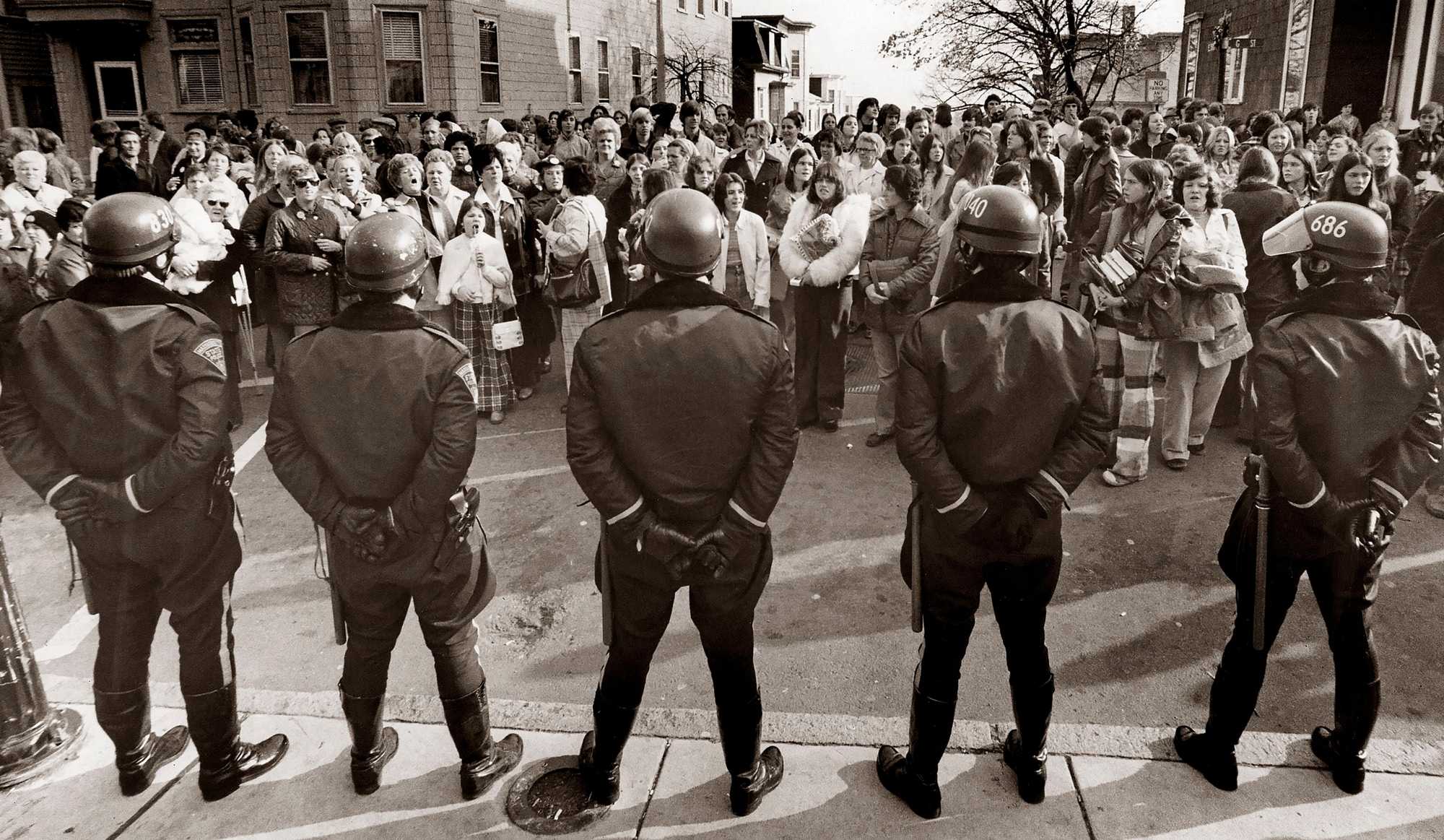 Police officers formed a line outside South Boston High School as parents and boycotting students held a demonstration on Nov. 25, 1974.