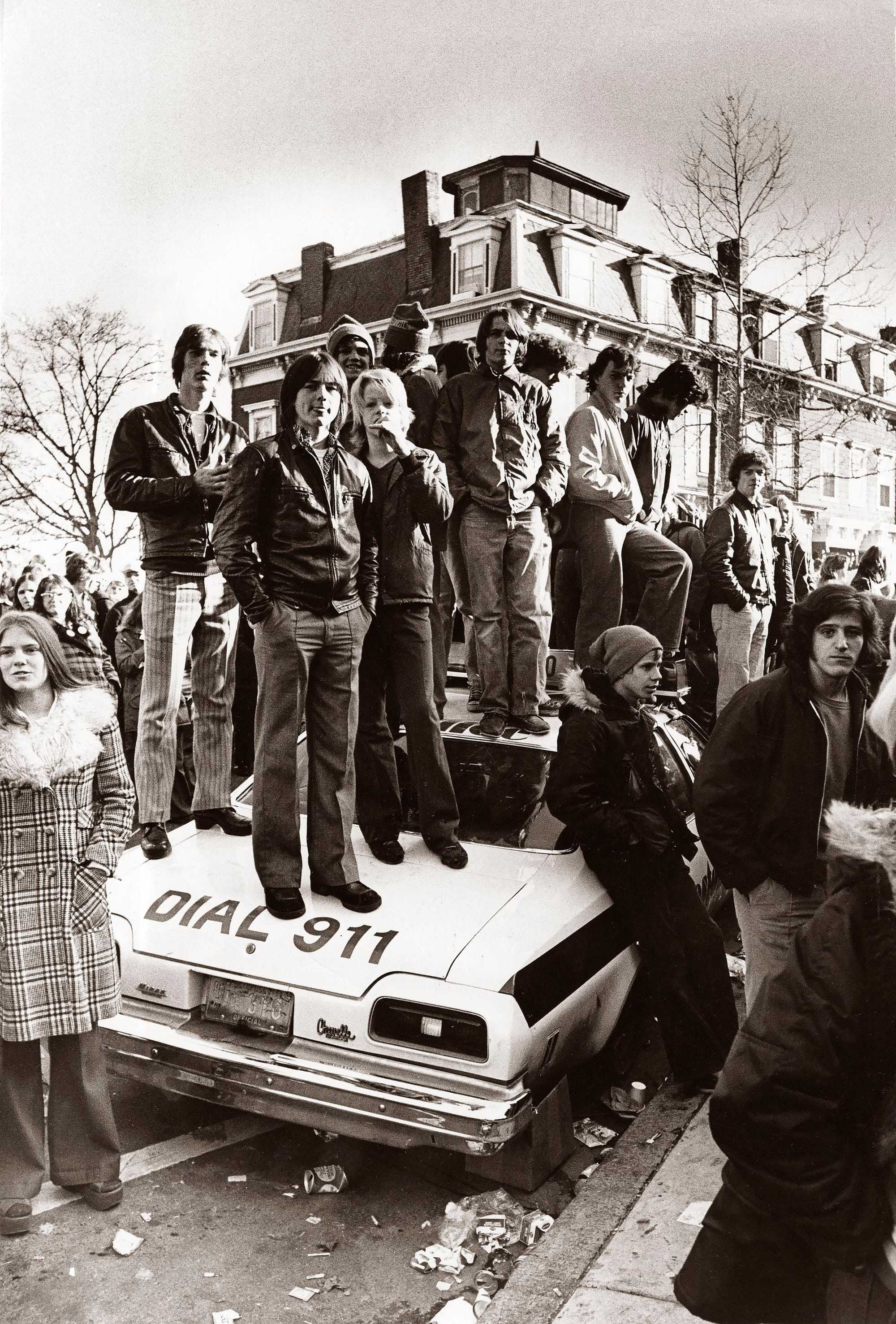 People stood on top of a police car after a Dec. 11, 1974, clash between police and a crowd of 1,500 people outside South Boston High School.