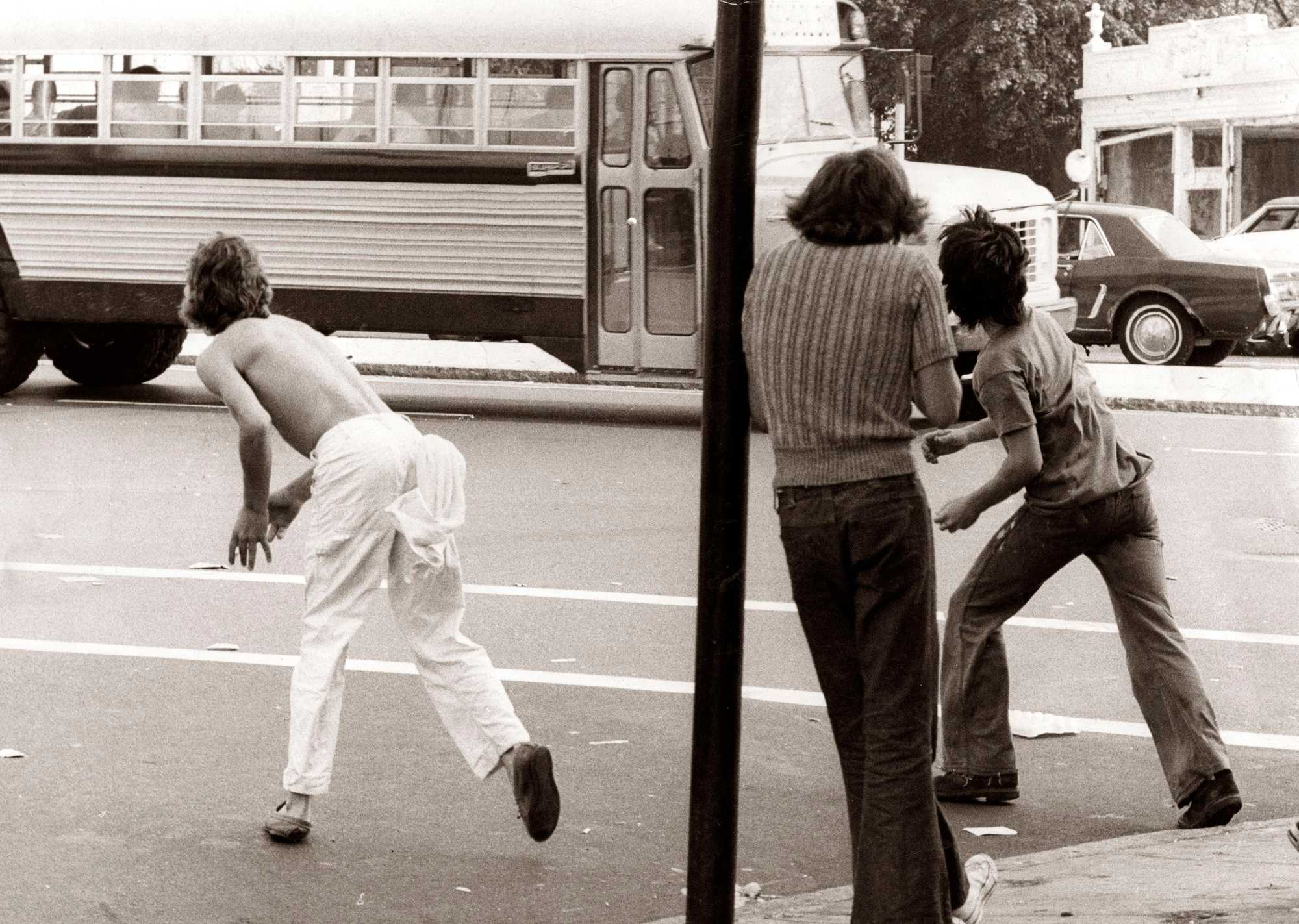 Two boys threw objects at a bus carrying Black students at Edward Everett Square in Dorchester on Sept. 12, 1974, the first day of school under the new busing system put in place to desegregate Boston Public Schools. 