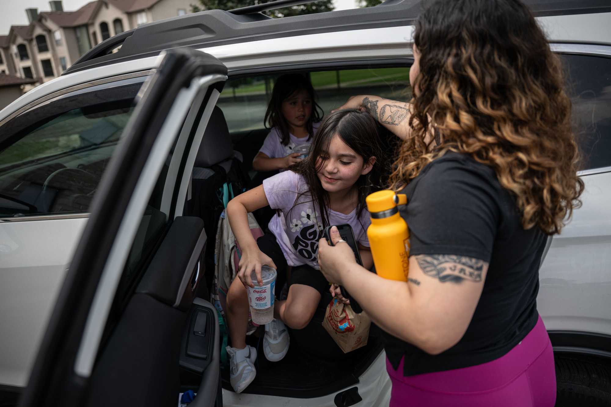 Selena Osuna helped her daughters, Maliah MacDuffee, 7, and Jae MacDuffee, 5, out of their car after picking them up from school. (Tamir Kalifa for The Boston Globe)