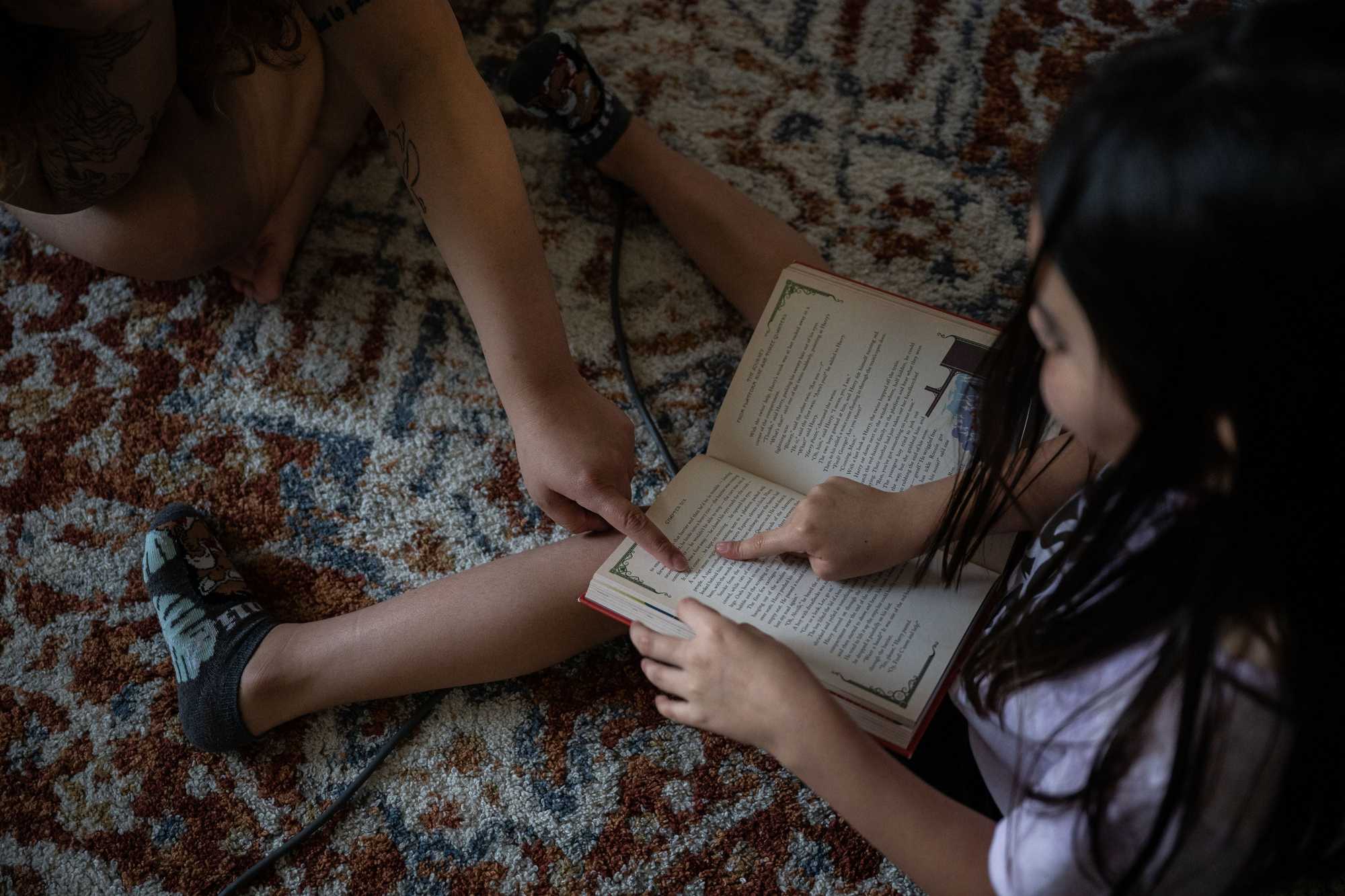 Maliah read a book with her mother and sister, Jae, at their apartment. (Tamir Kalifa for The Boston Globe)