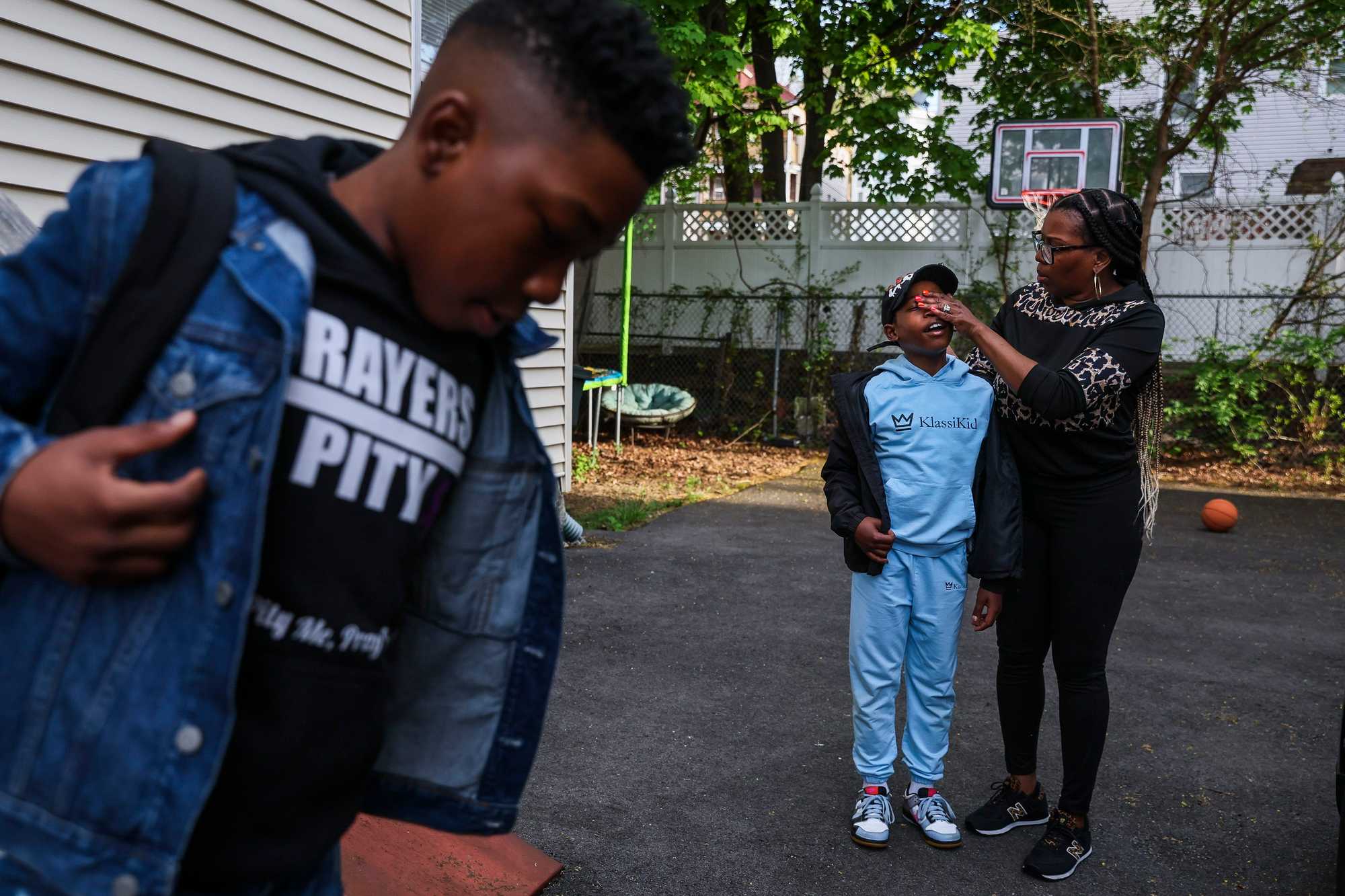 avaj King put on his backpack while his mother, Kueen, wiped the face of his brother, Tairih. (Erin Clark/Globe Staff)

