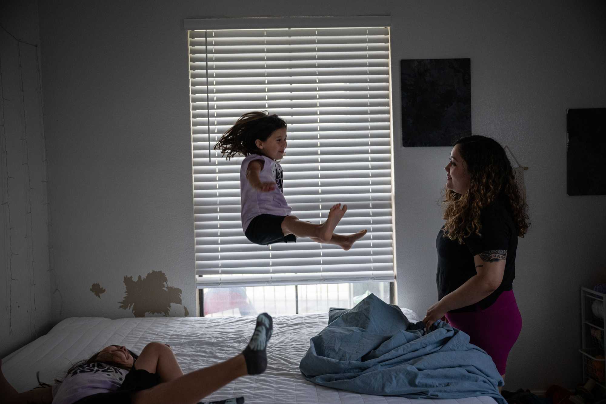 Osuna played with her daughters Maliah (left) and Jae as she changed the sheets on her bed. (Tamir Kalifa for The Boston Globe)