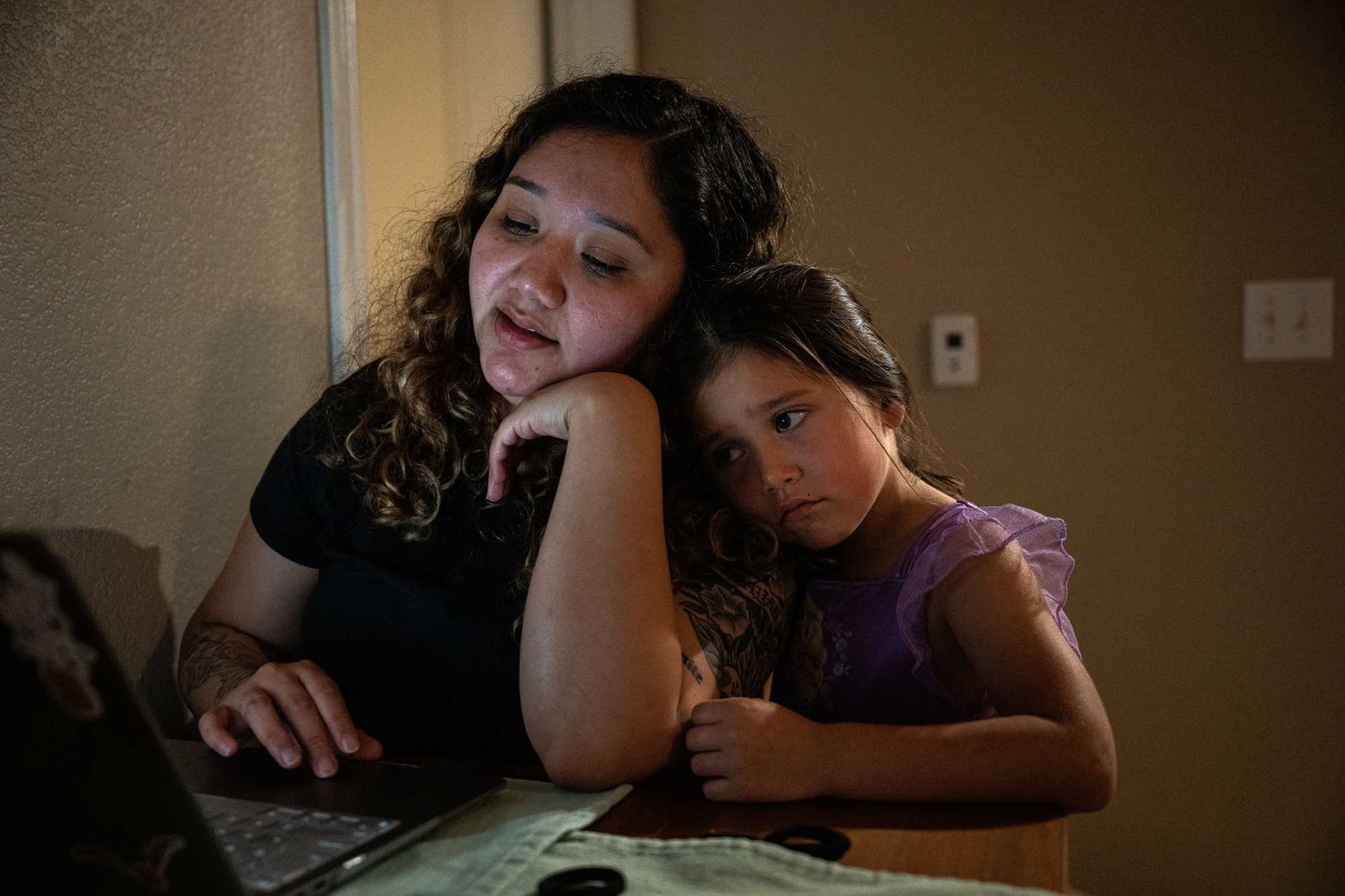 Jae MacDuffee, 5, leaned on her mother, Selena Osuna, as she worked on an essay for her Texas State University social work program at her apartment in Hutto, Texas. (Tamir Kalifa for The Boston Globe)