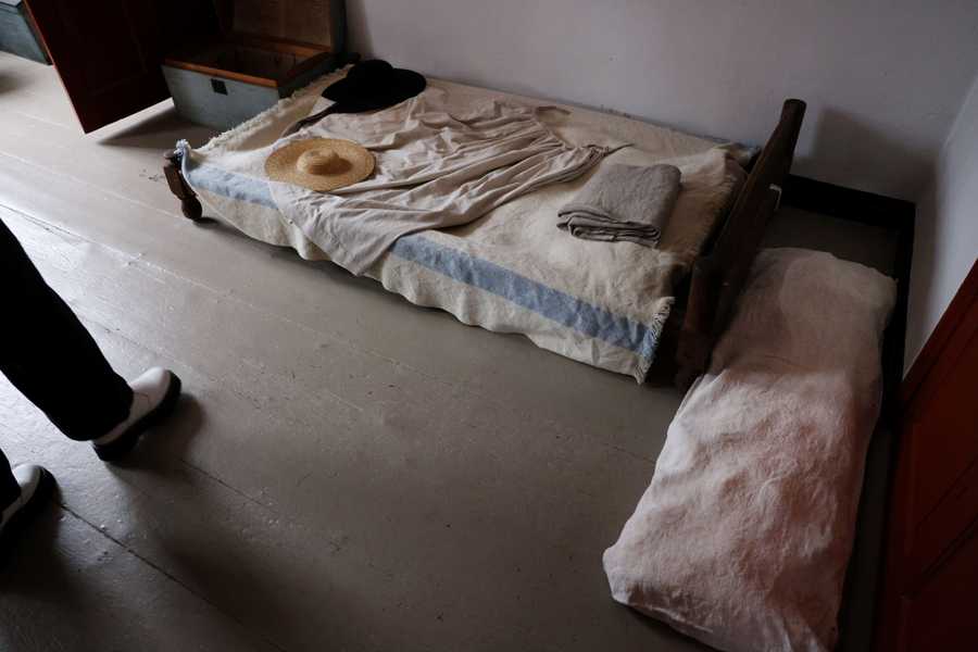 Medford, MA - 2/21/2023: Executive Director Kyera Singleton talks about the Kitchen Chamber Room while touring the Royall House and Slave Quarters in Medford, MA on February 21, 2023. She said that enslaved people that worked in the chamber also slept there, pointing out the small bed and full-length pillow in the corner of the room. (Craig F. Walker/Globe Staff) (chamber used for sewing and fitting) 