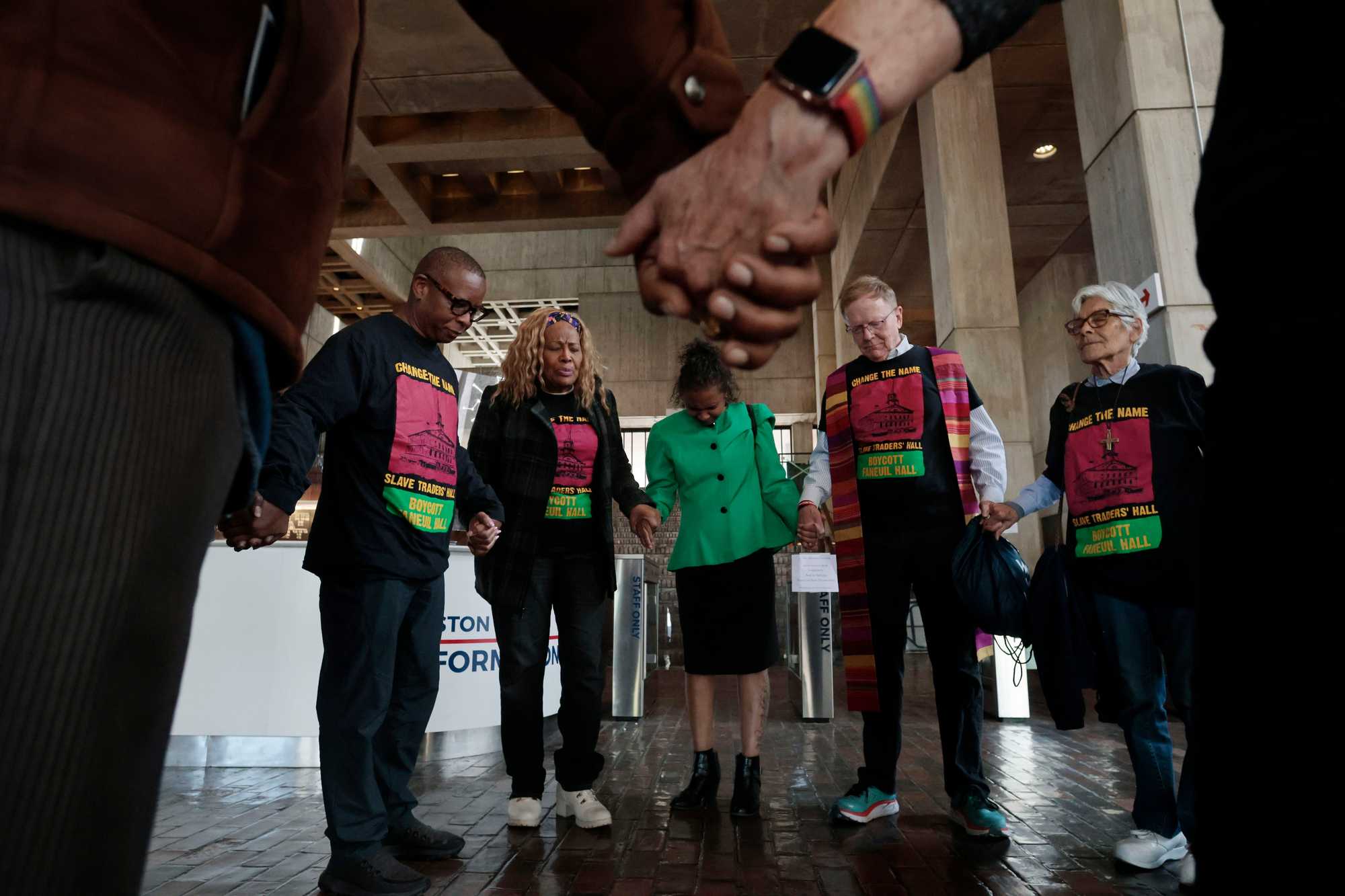 From left, Rev. Kevin Peterson, founder and executive director of The New Democracy Coalition, Pastor Pamela Kelly, Izabel Depina, Rev. John Gibbons, and Sister Rita Raboin prayed in the lobby at Boston City Hall after delivering a petition to the office of City Council President Ed Flynn on May 19. As a part of an ongoing campaign to change the name of Faneuil Hall, local activists delivered 3,000 petition signatures.
