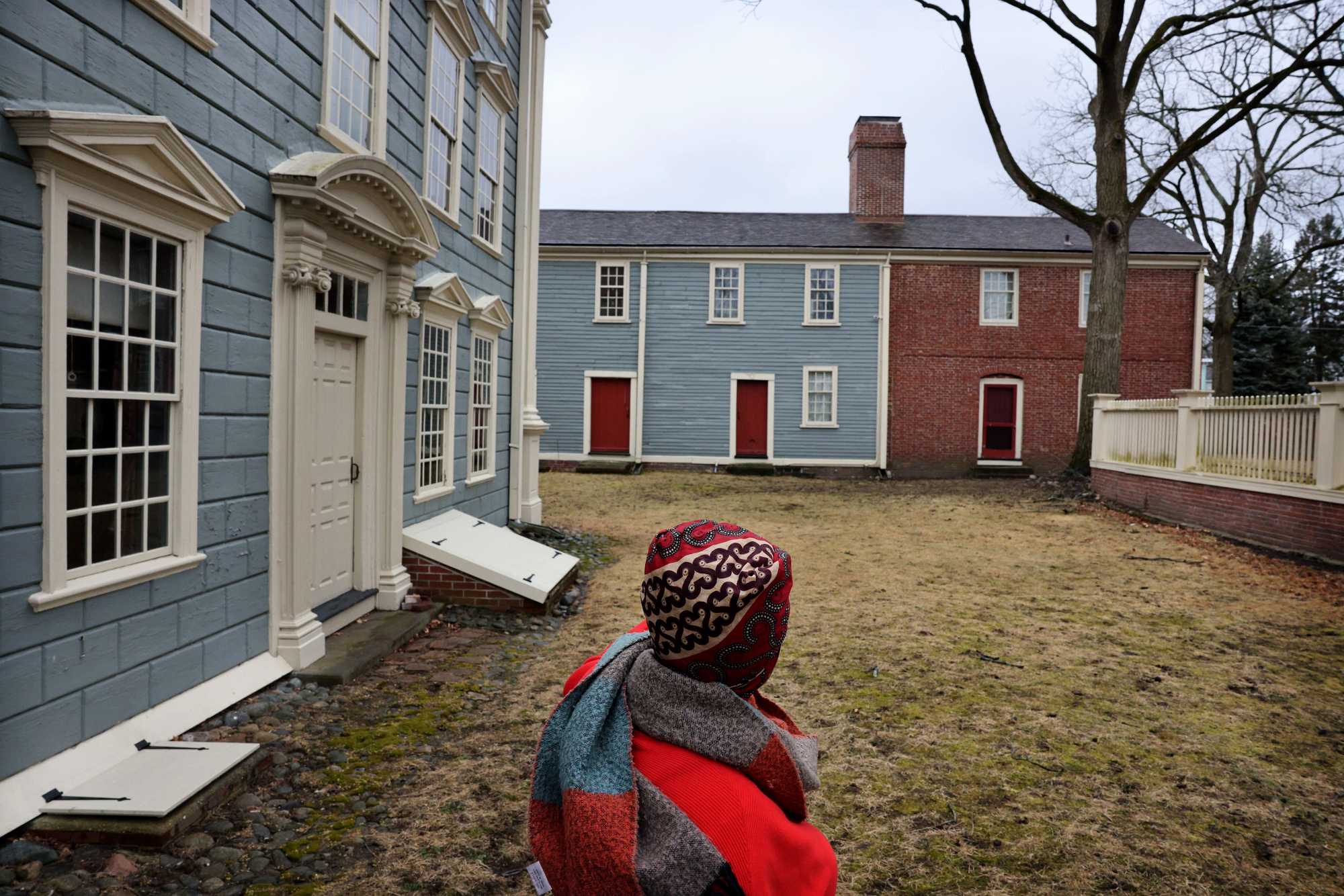 Slavery was common in parts of the Massachusetts Bay Colony. Executive director Kyera Singleton walked the grounds of the Royall House and Slave Quarters in Medford, an estate that once held the largest number of slaves in Colonial Massachusetts. At left is the Big House, where the family lived, as well as some of the enslaved people. Straight ahead is the Slave Quarters.