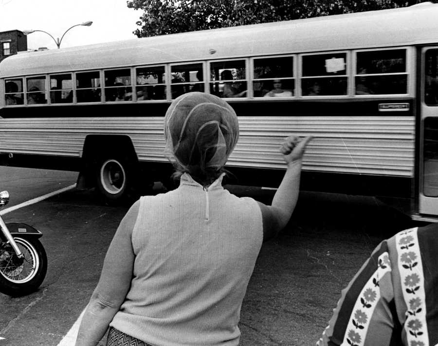 A woman gestured for students being bused home to Roxbury to "go home and stay home," as a school bus left Patrick F. Gavin Middle School in South Boston on Sept. 17, 1974, during the first full week of school under the new busing system put in place to desegregate Boston Public Schools. (Charles Dixon/Globe Staff) 