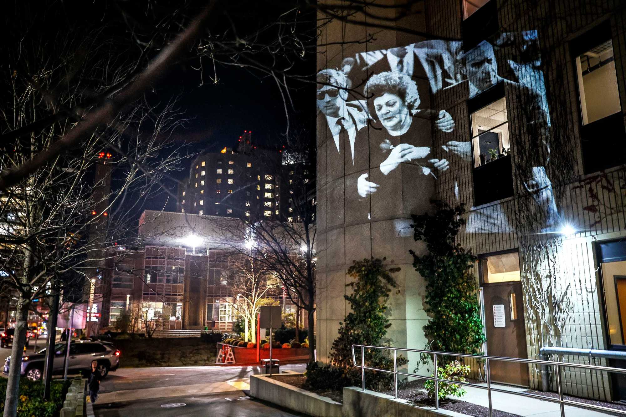 A photograph of Evelyn DiMaiti at her daughter Carol's funeral in 1989 is projected outside of Brigham and Women’s Hospital. Carol, who had just left a birthing class at the hospital, was taken back to the Brigham after being shot in nearby Mission Hill. 