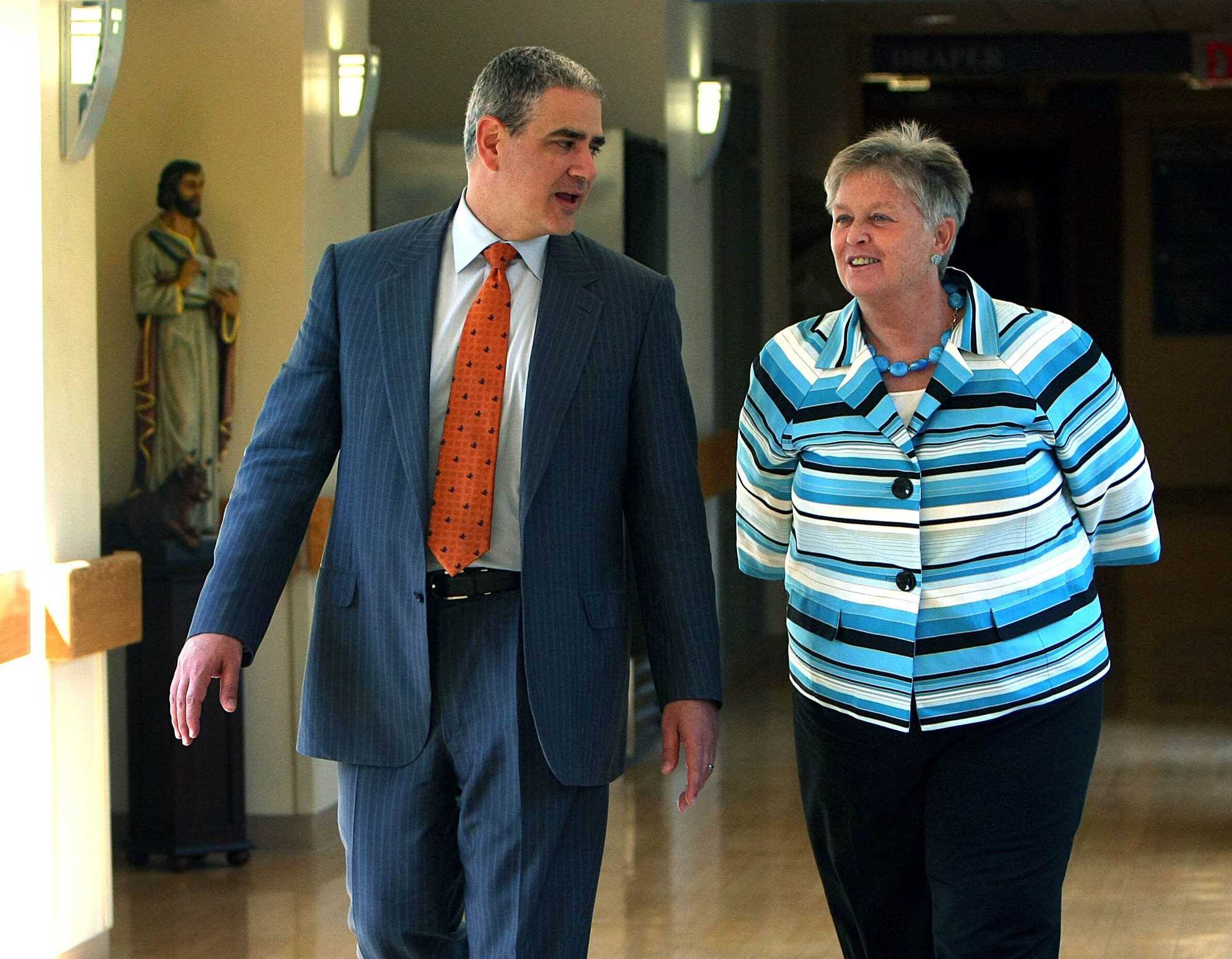 Dr. Ralph de la Torre, then CEO of Caritas Christi Health Care, talked with Norwood Hospital President Margaret Hanson as they walked to a meeting in 2009. Behind them is a statue of St. Luke, the patron saint of doctors.