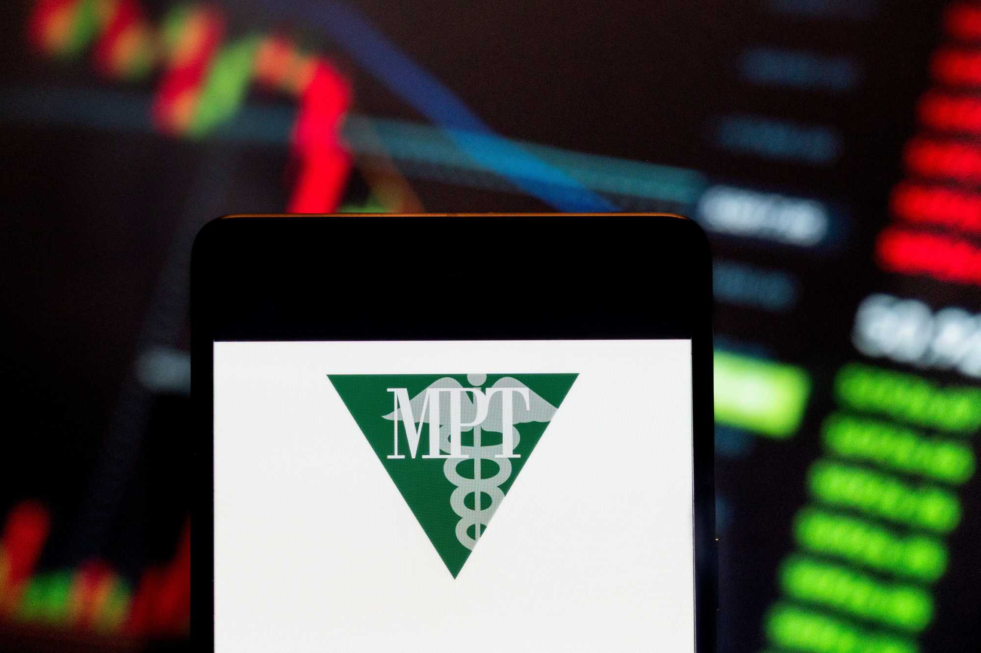 In this photo illustration, the logo of Medical Properties Trust, a real estate investment trust that invests in health care facilities, was displayed on a smartphone with an economic stock exchange index graph in the background.