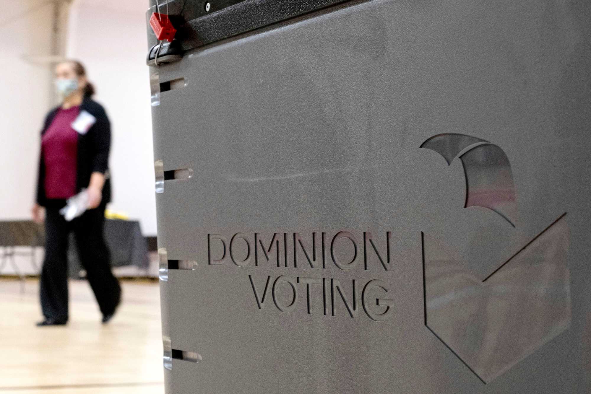 A worker passed a Dominion Voting Systems ballot scanner while setting up a polling location at an elementary school in Gwinnett County, Ga., outside of Atlanta on Jan. 4, 2021. 