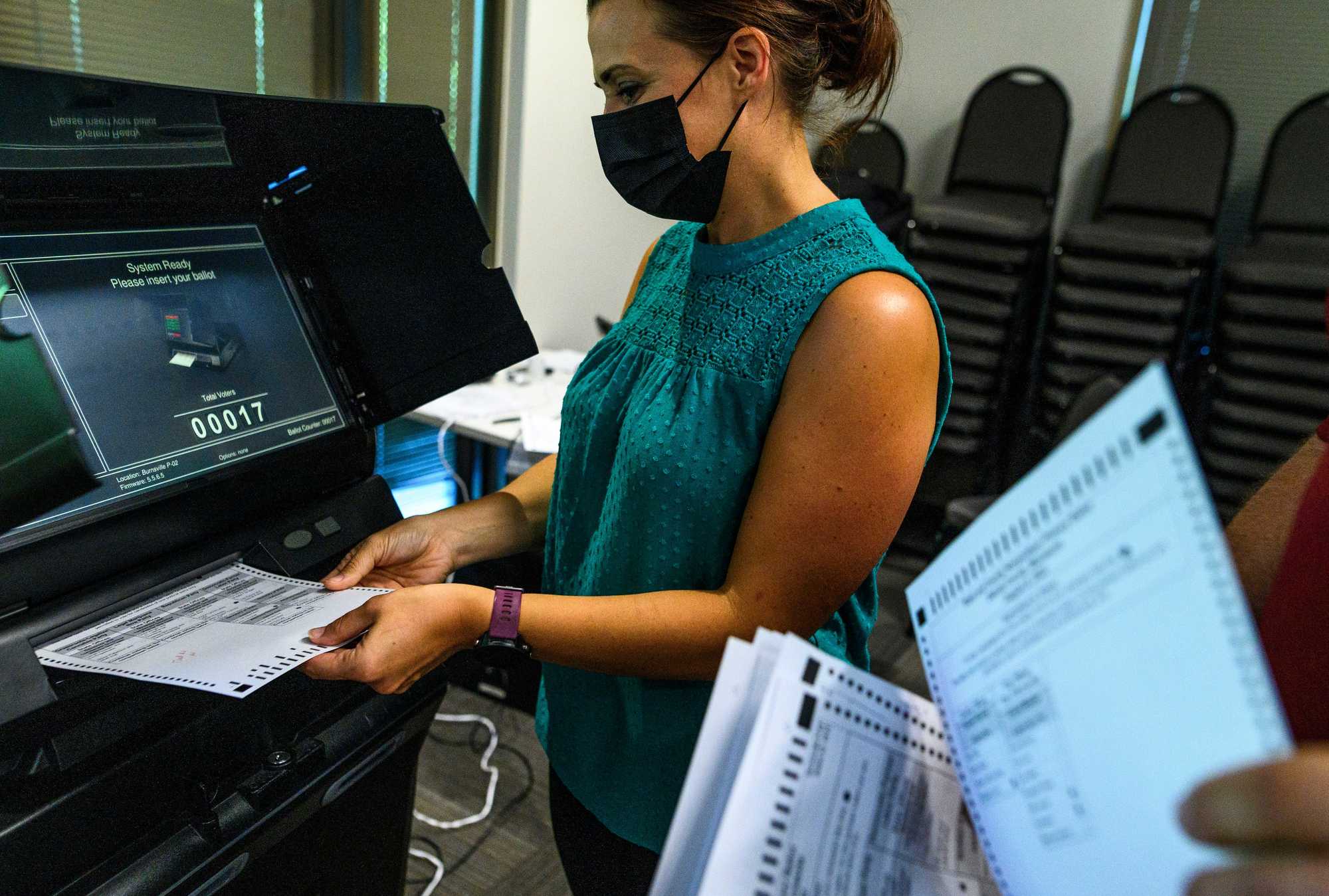 Election judges submitted test ballots into a machine during a public accuracy test of voting equipment on Aug. 3 in Burnsville, Minn.