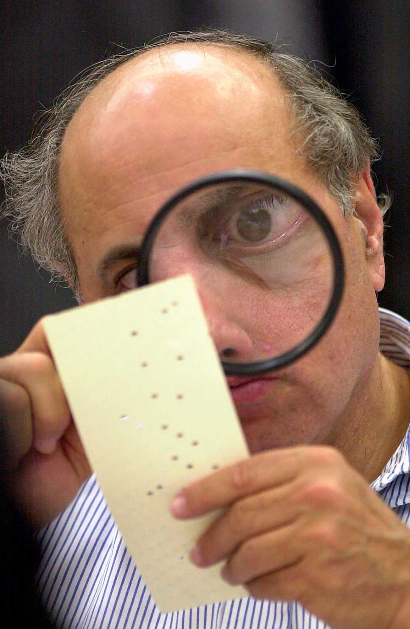 Judge Robert Rosenberg, a member of the Broward County, Fla., canvassing board, used a magnifying glass to examine a disputed election ballot in Fort Lauderdale on Nov. 24, 2000.