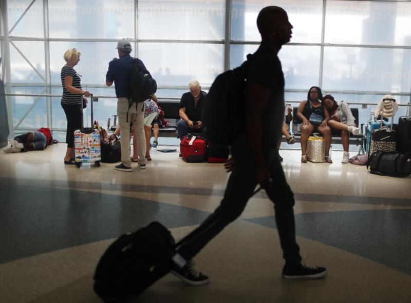 Silhouette of a man walking in an airport while passengers are seen waiting in the background