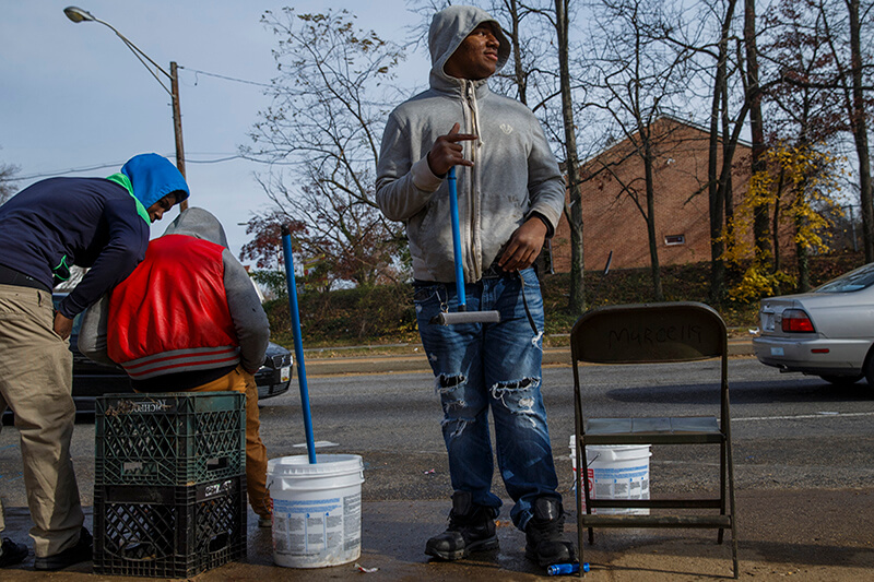 Ronald Robinson stands on a corner waiting to clean the windows of stopped cars in Baltimore.